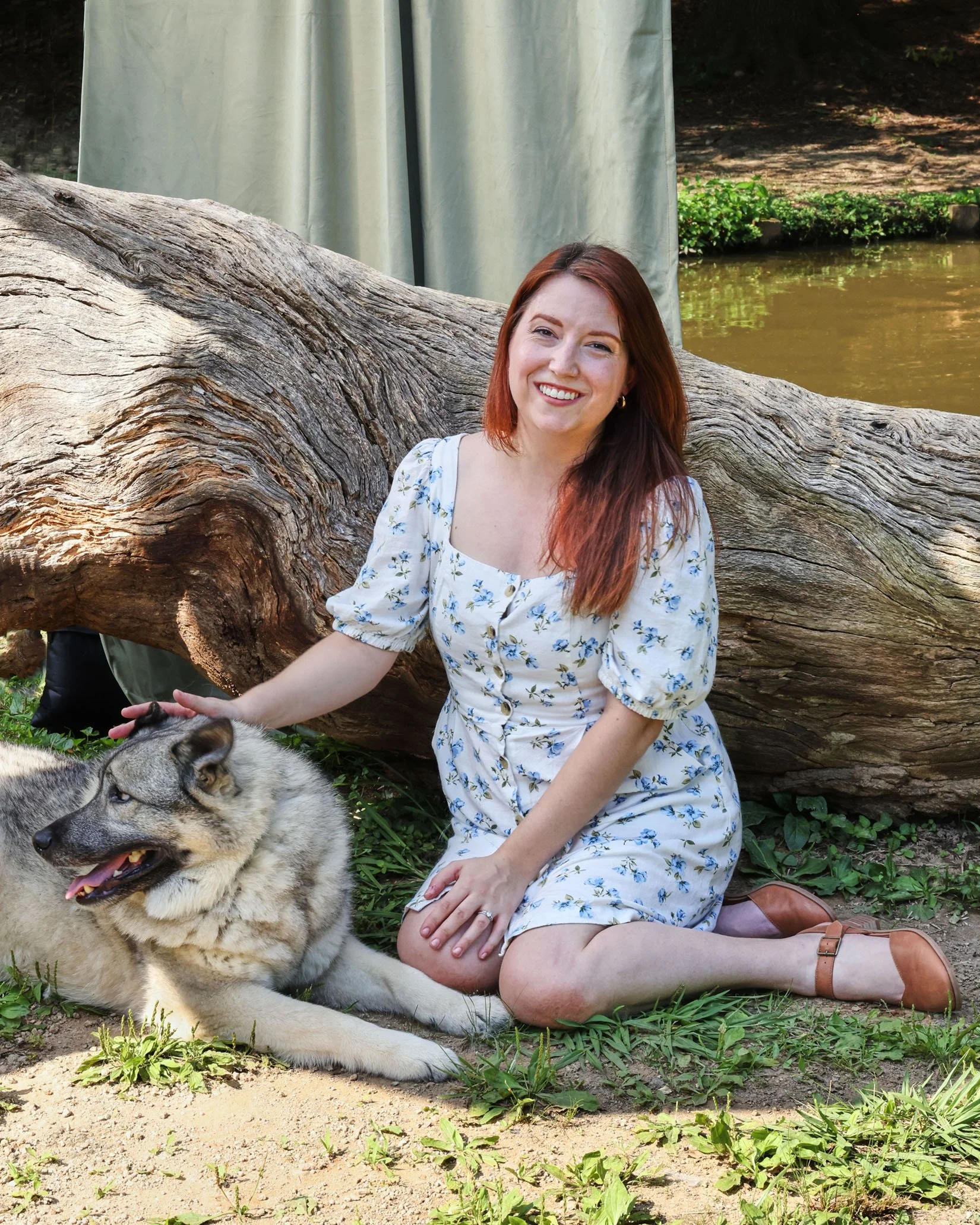 Red headed woman sitting with dog on the grass
