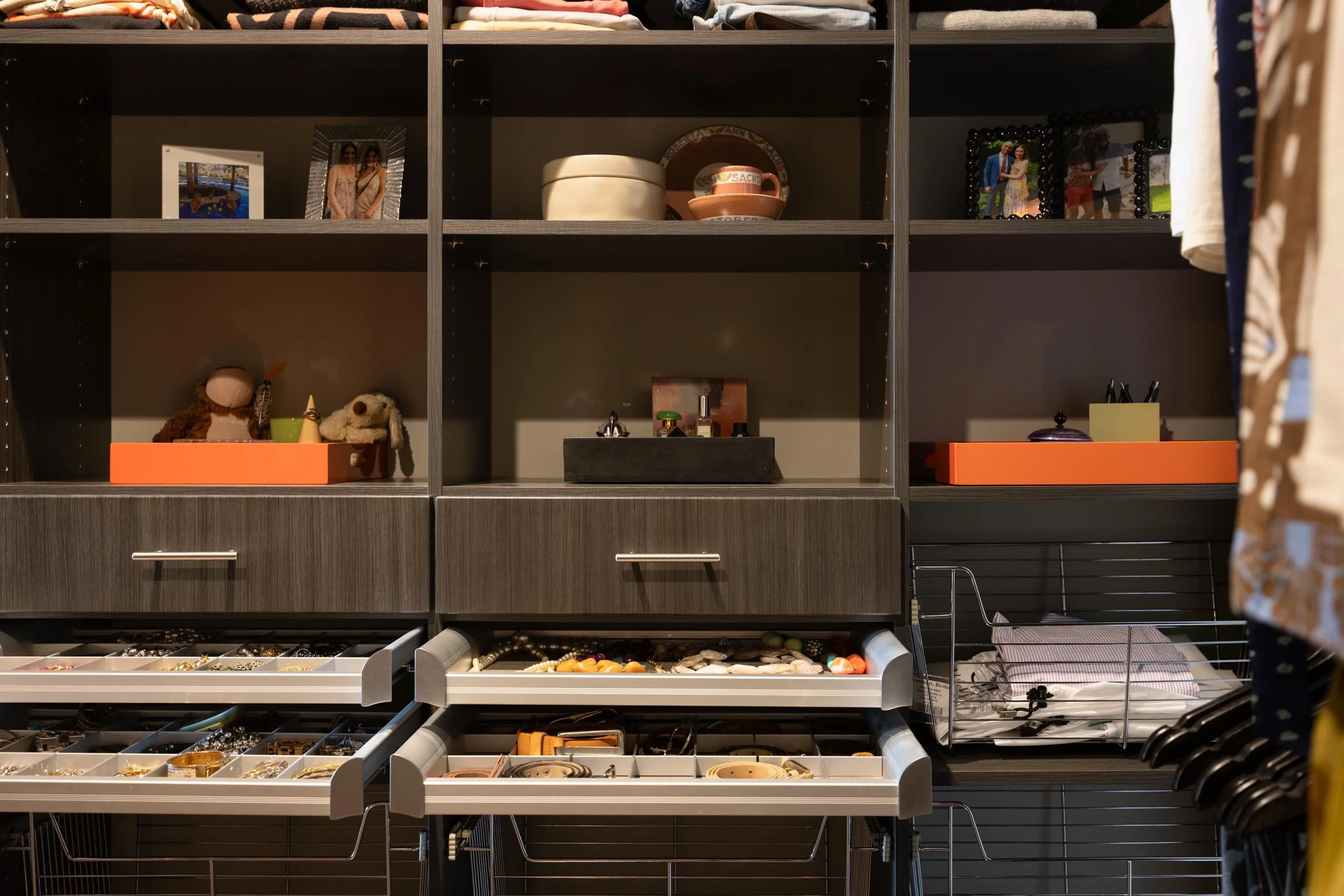 Walk-in bedroom closet with custom display shelves for photos, jewelry, accessories, and clothes.