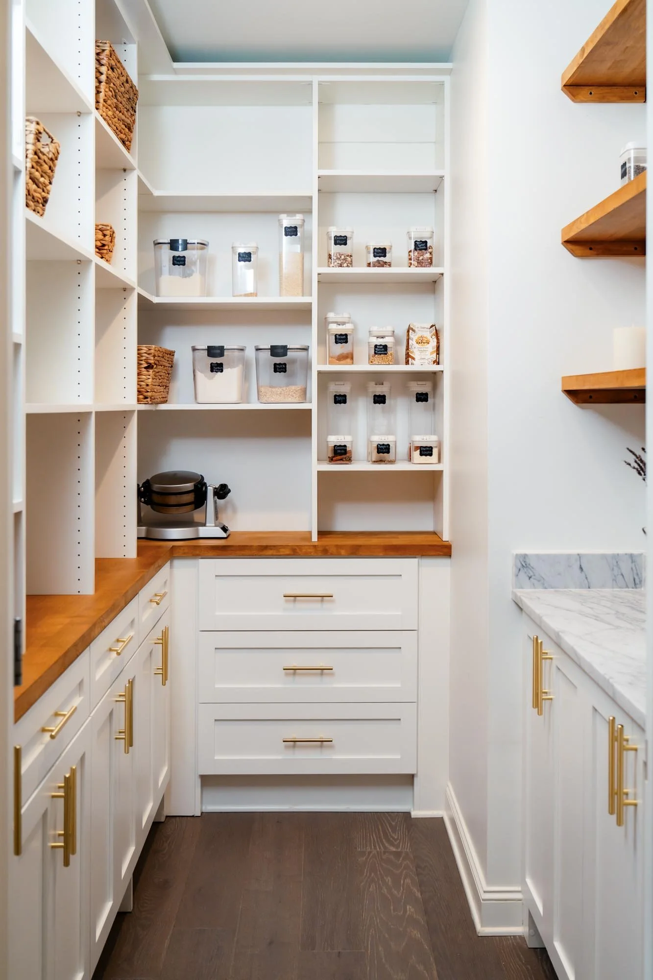 Walk-in pantry with white custom shelving and storage, wooden countertops, and accent lighting in Central Ohio.
