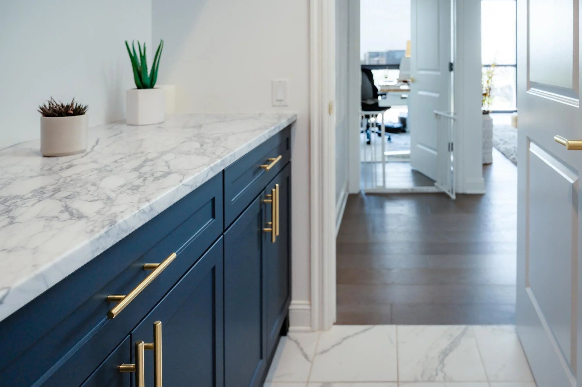 Custom laundry room storage and blue cabinetry with white marble countertop leading to a home office area in Columbus, Ohio.