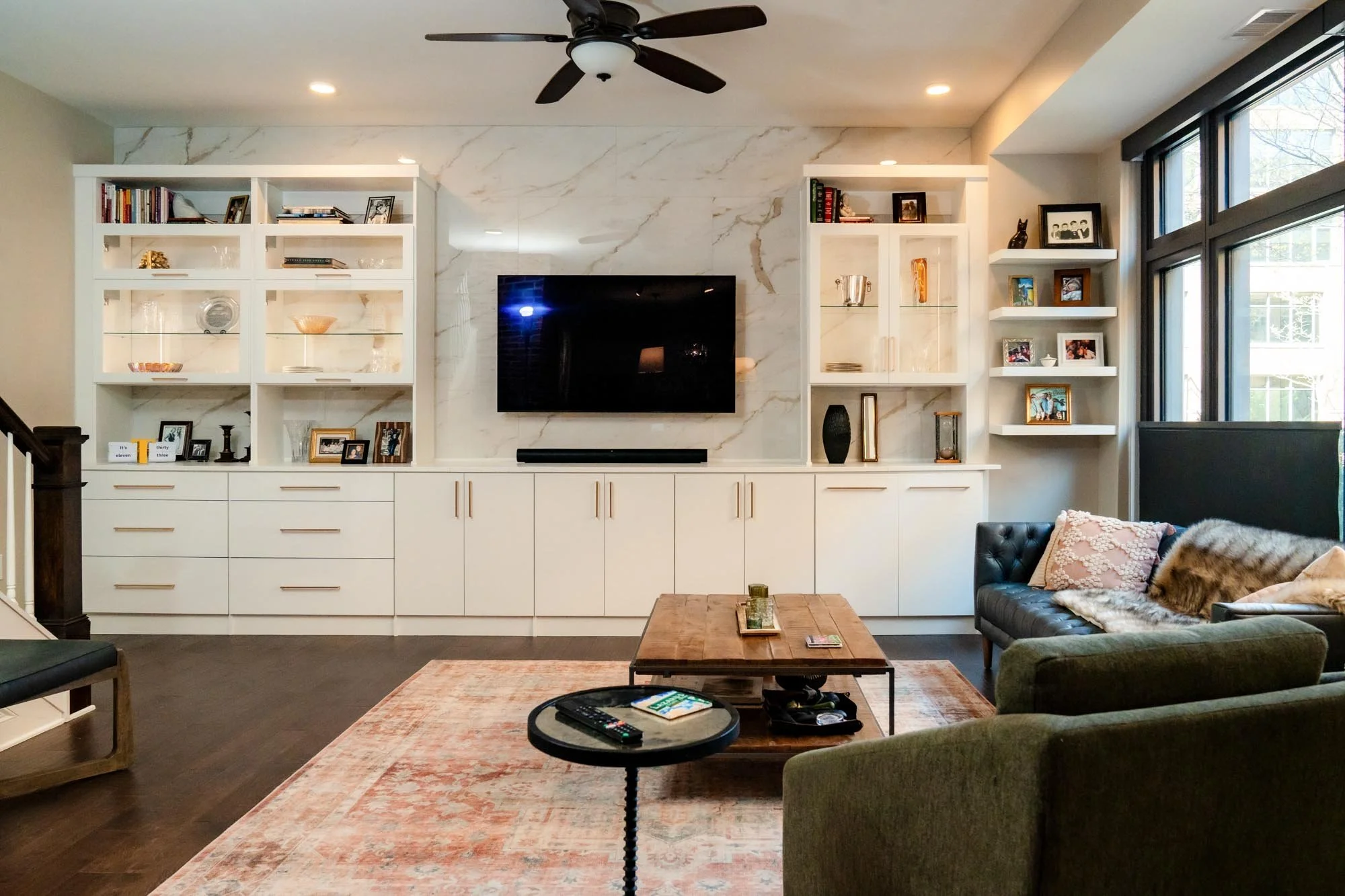 Living room featuring a white built-in shelving unit and storage with custom accent lighting and beautiful architectural details in Columbus, Ohio.