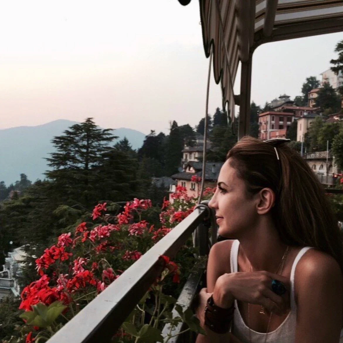 Layla Maris seated on a balcony overlooking Lake Como, reflecting on landscape and place.