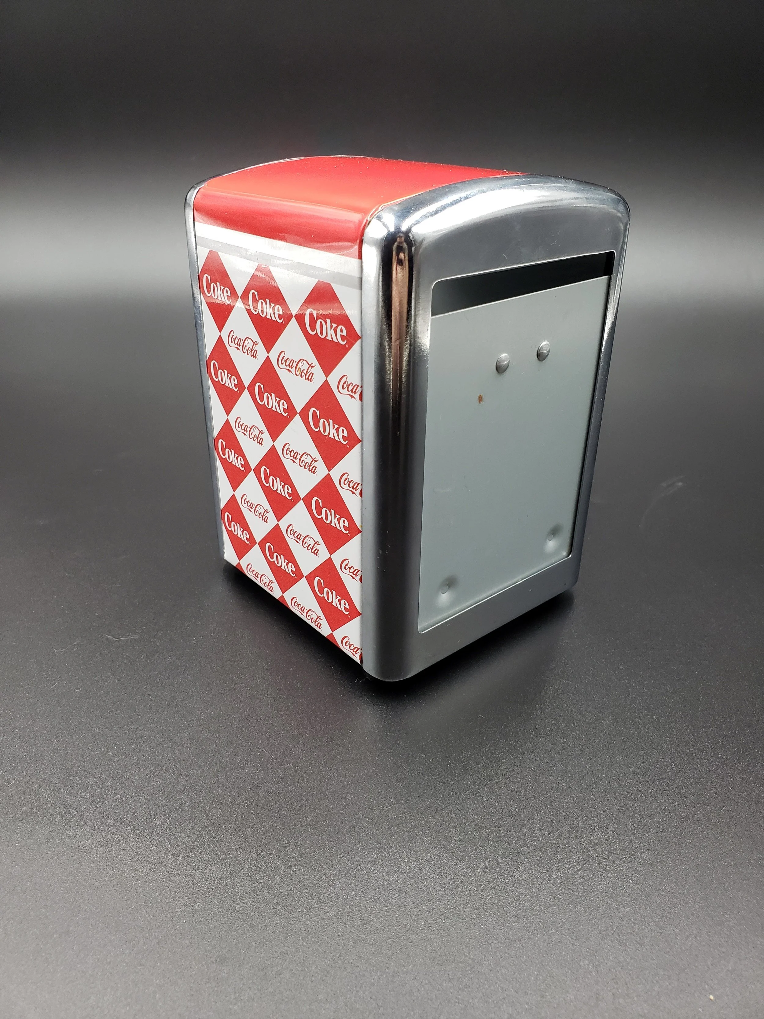 A miniature vintage Coca-Cola vending machine with a red top, silver sides, and patterned side panels featuring red diamonds with white 'Coke' and 'Coca-Cola' logos.