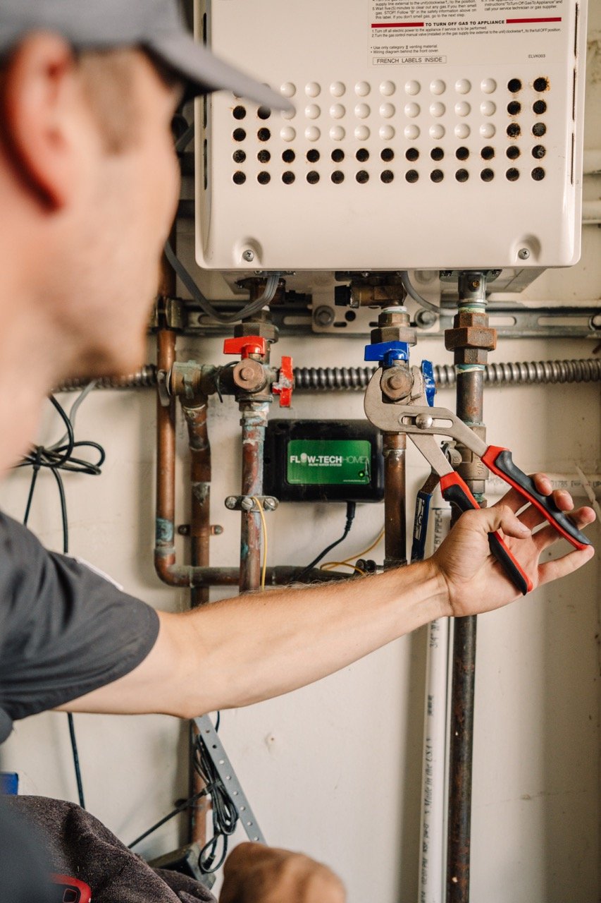 white caucasian male Econo air plumber tightening water valve on a water heater