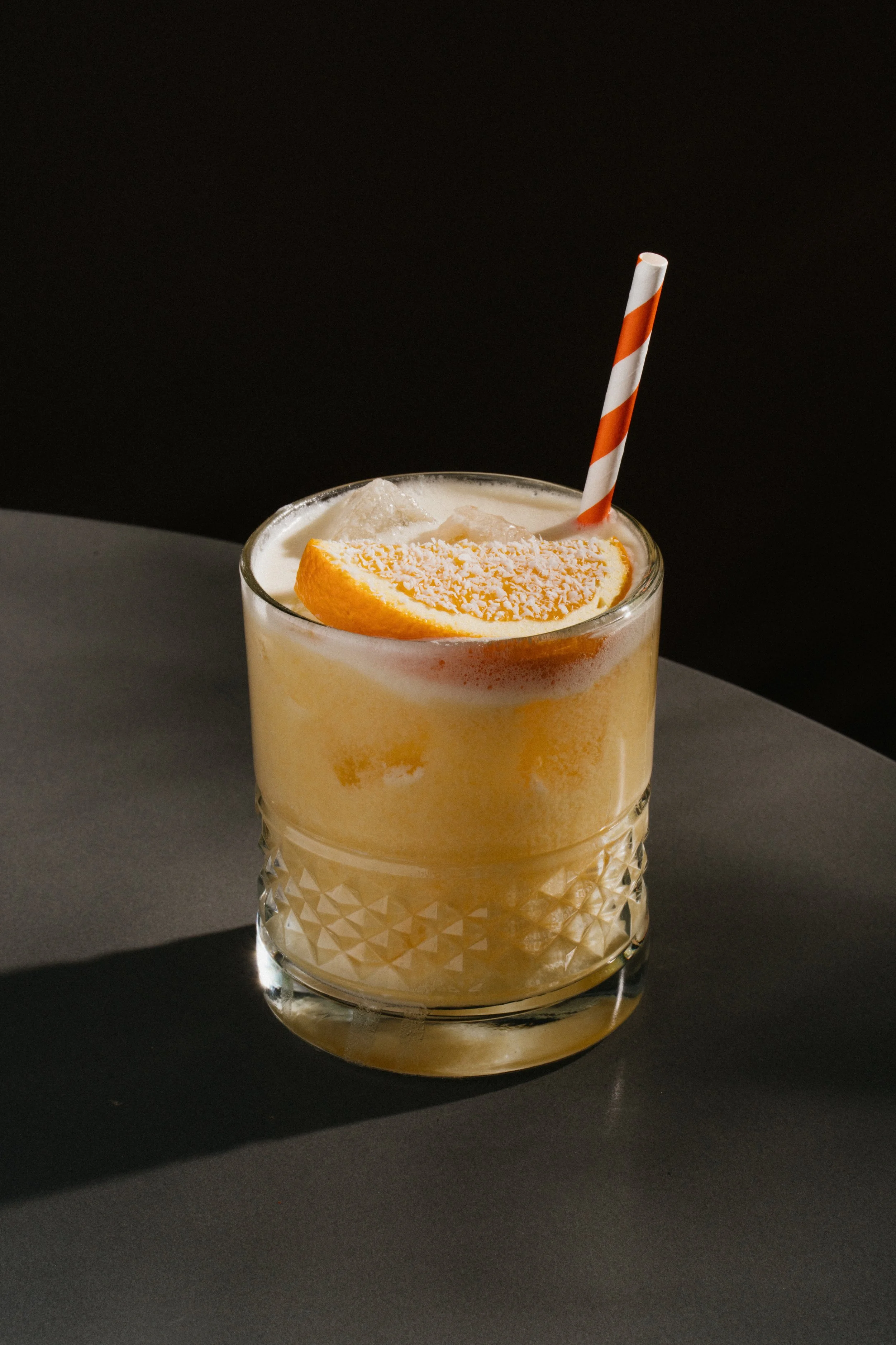 A creamy orange cocktail in a rocks glass garnished with an orange
