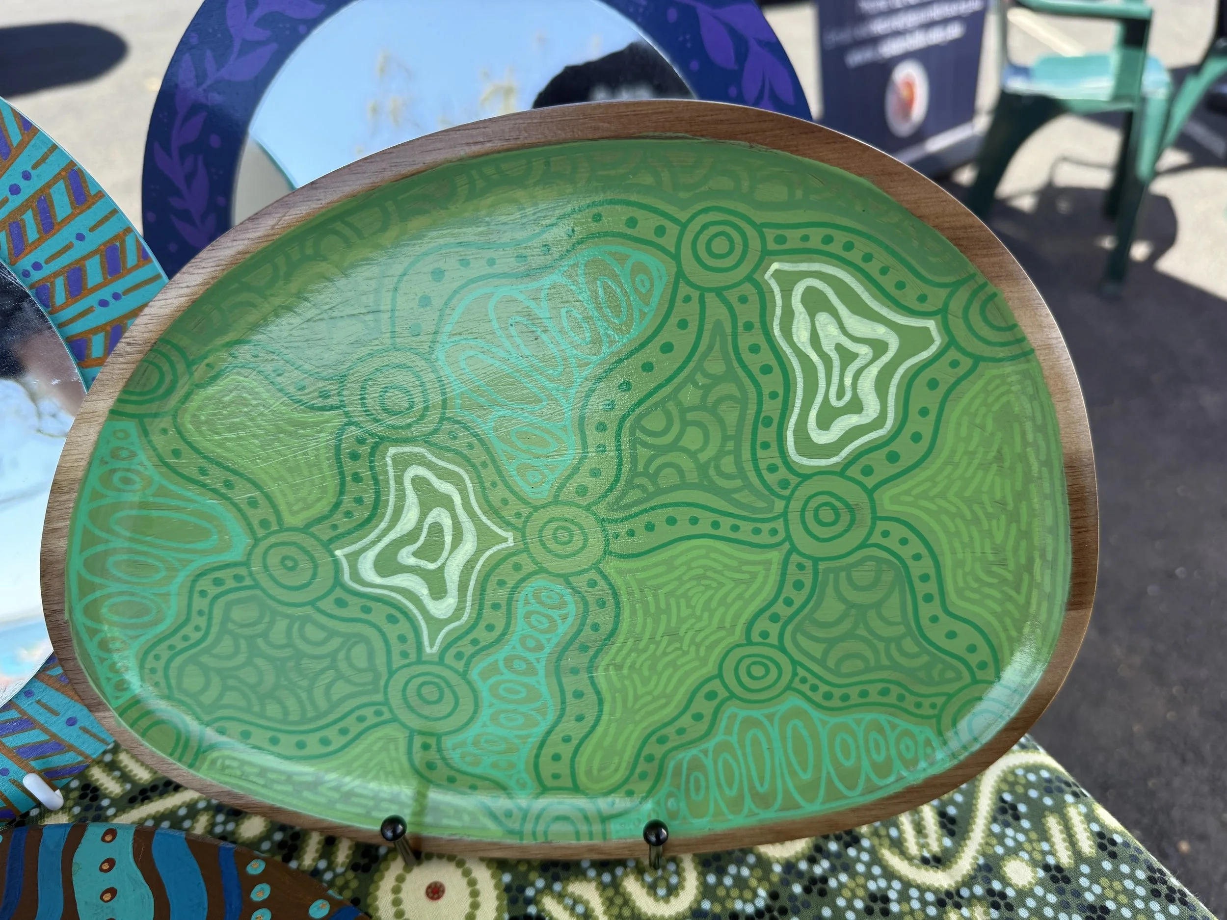 Decorative oval plate with a bright green surface featuring abstract patterns in white, turquoise, and darker green.