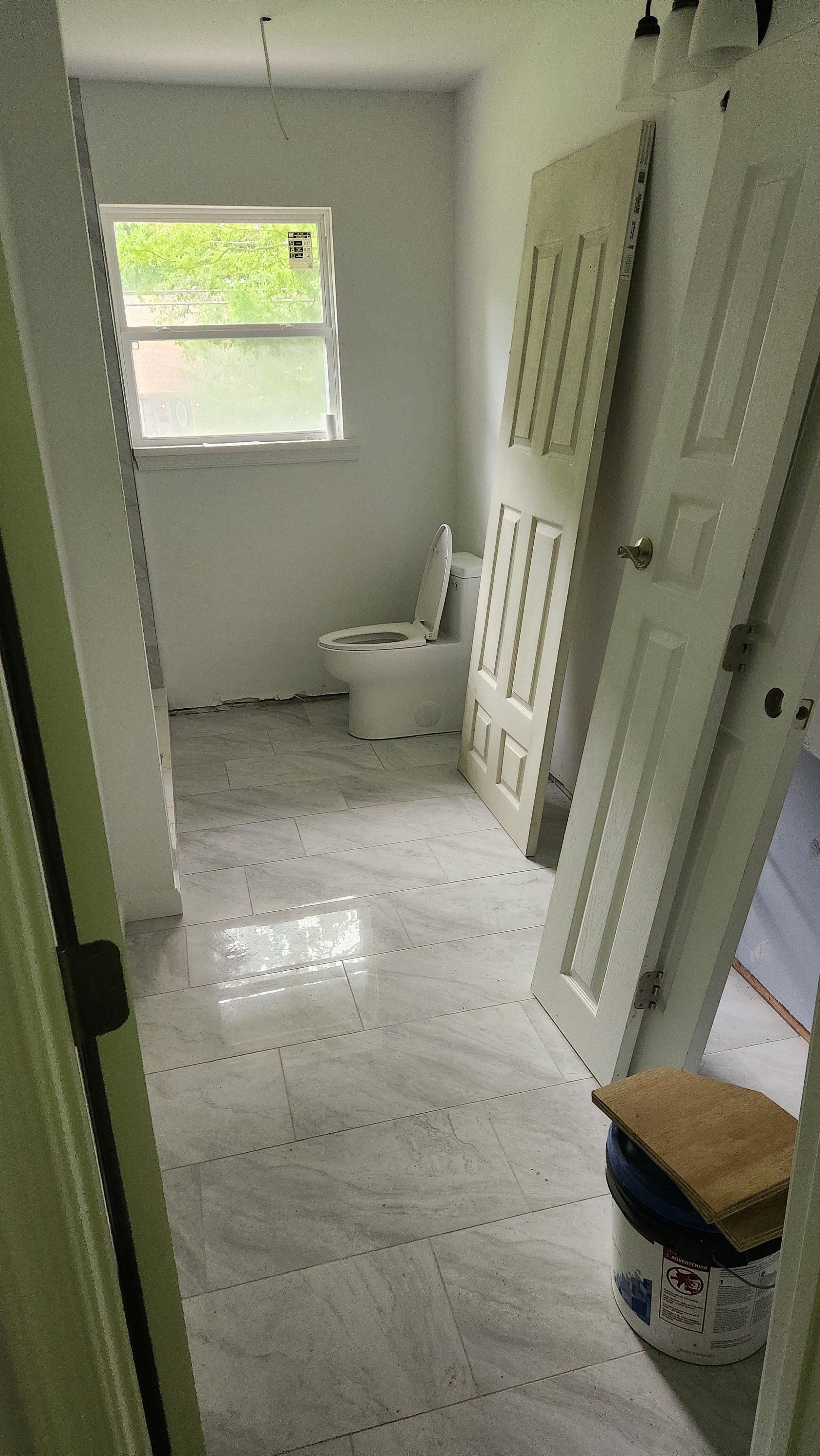A bathroom under renovation with new tile, a toilet, and interior doors waiting to be hung.