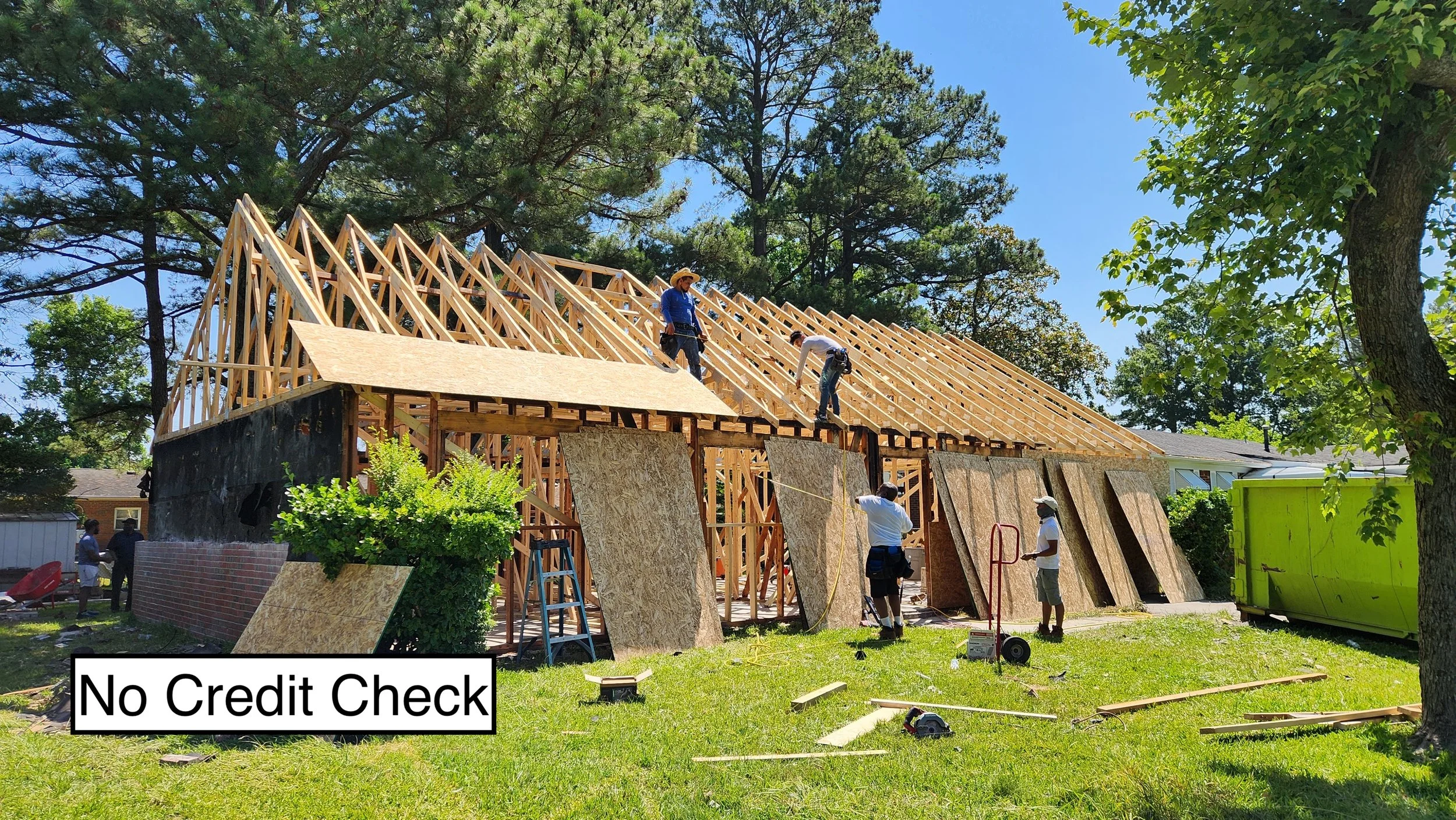 Construction workers framing a house on a sunny day with a caption reading "No Credit Check".