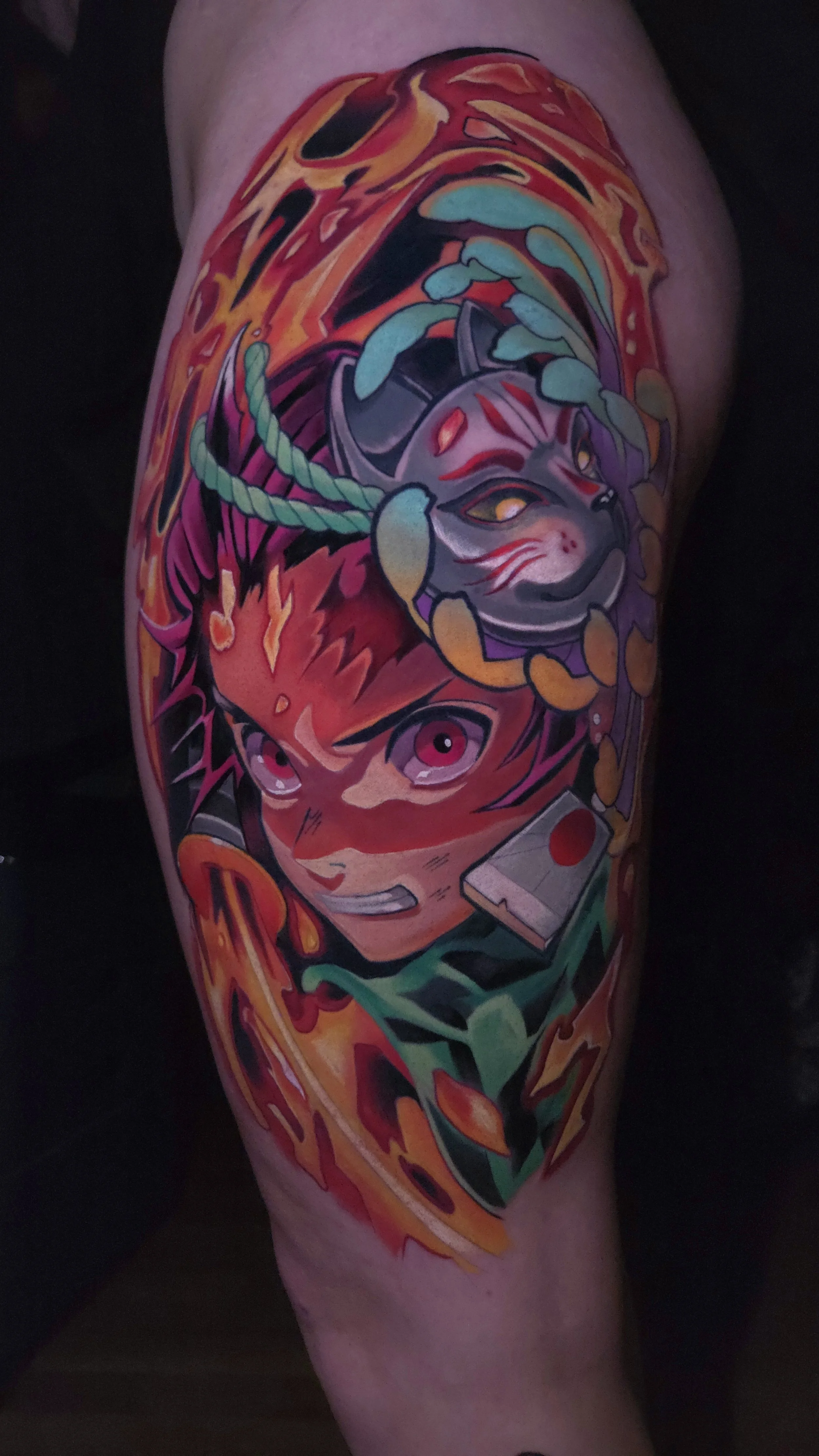 Colorful tattoo of a character with spiky hair and pink eyes, alongside a fox-like creature with a mask, surrounded by fiery and vibrant abstract elements.