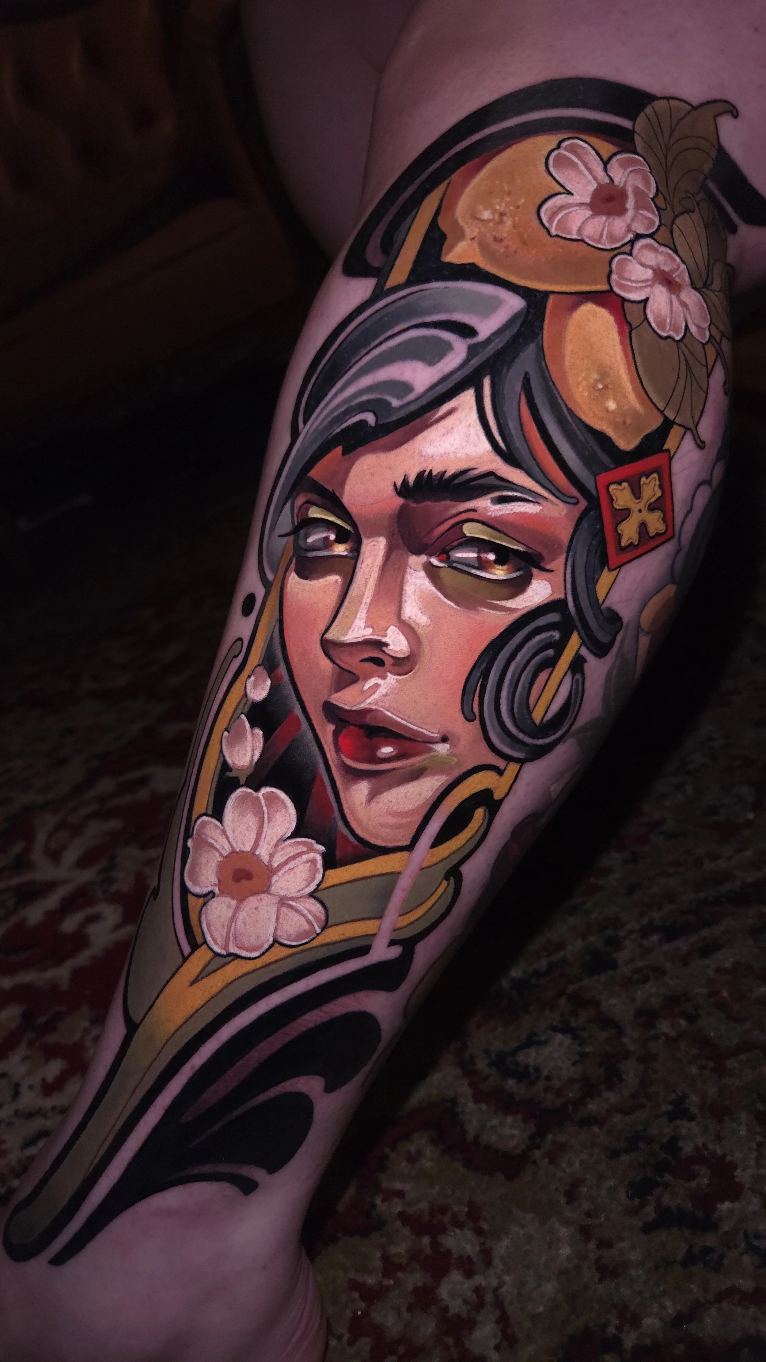 A colorful tattoo of a woman's face with flowers and abstract design elements on a person's arm.