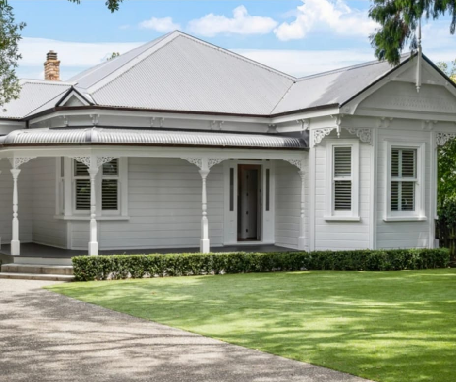 White Victorian-style house with decorative trim, front porch with columns, and a well-maintained lawn.