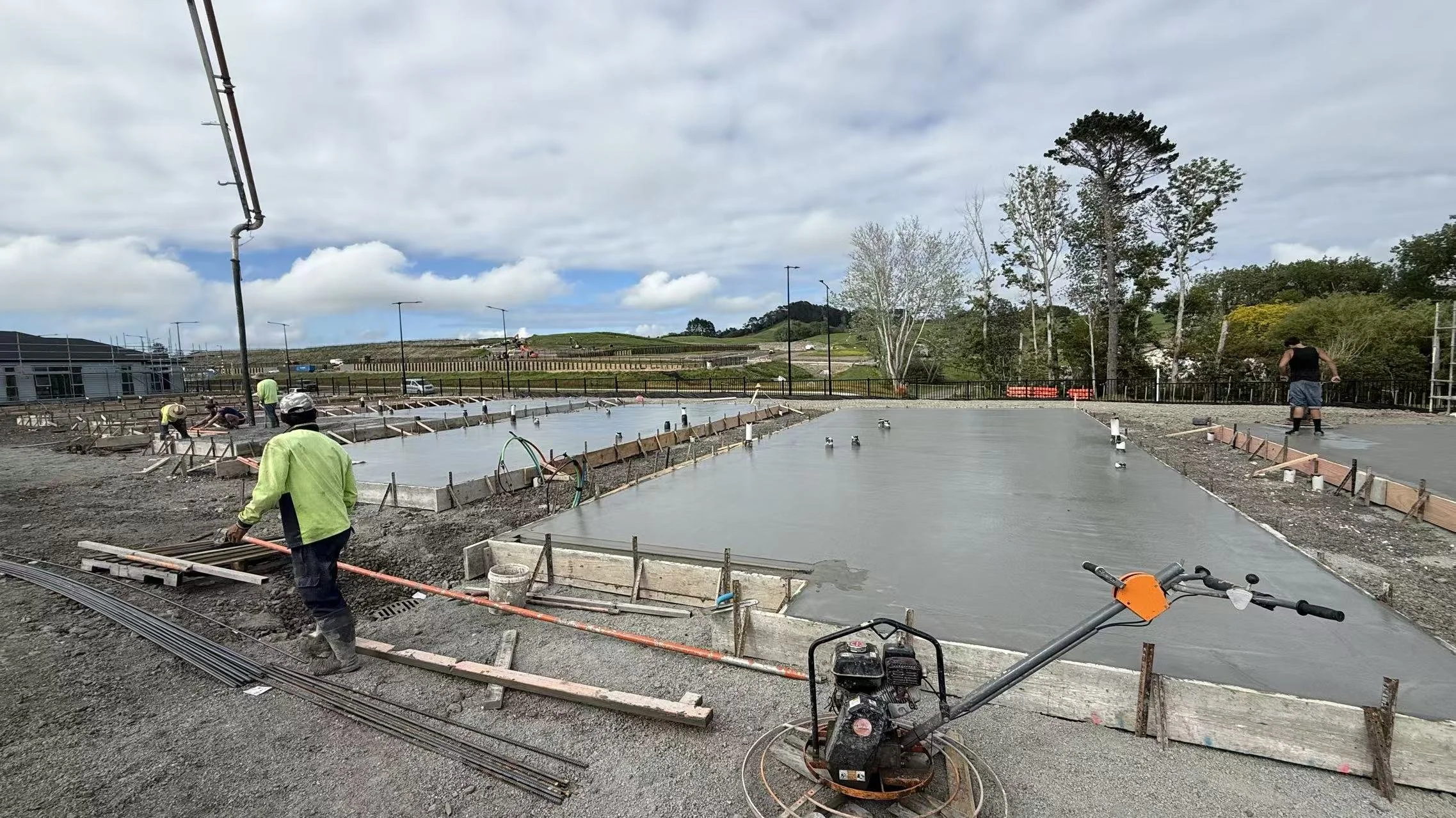 Professional concrete laying for a multi-unit development in Auckland, featuring the finishing of a 5-lot RibRaft foundation slab with structural formwork and a power trowel in the foreground.