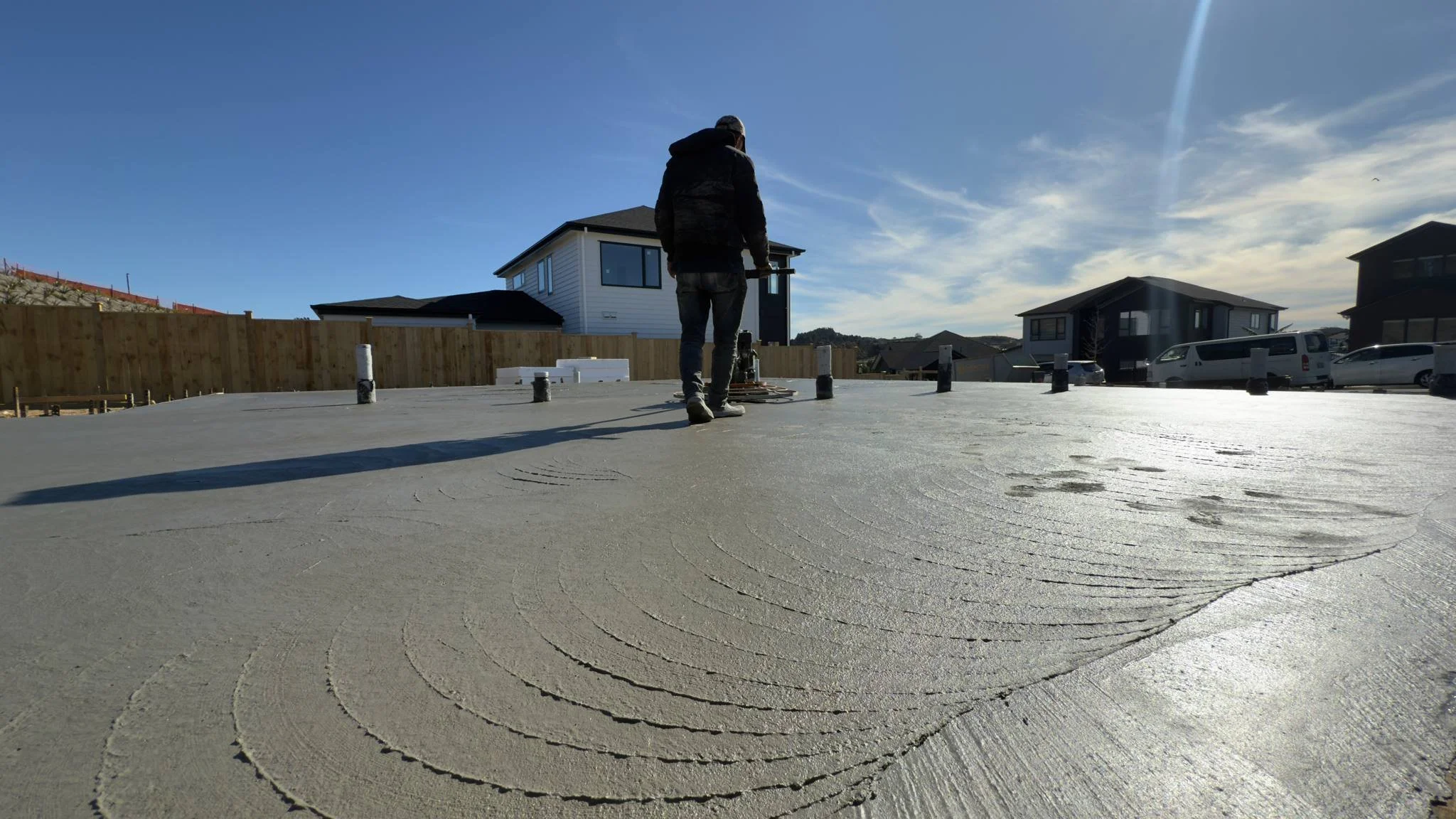 Professional power trowel finishing of a large-scale residential concrete slab in Auckland, achieving a smooth, high-spec surface for a modern home foundation.