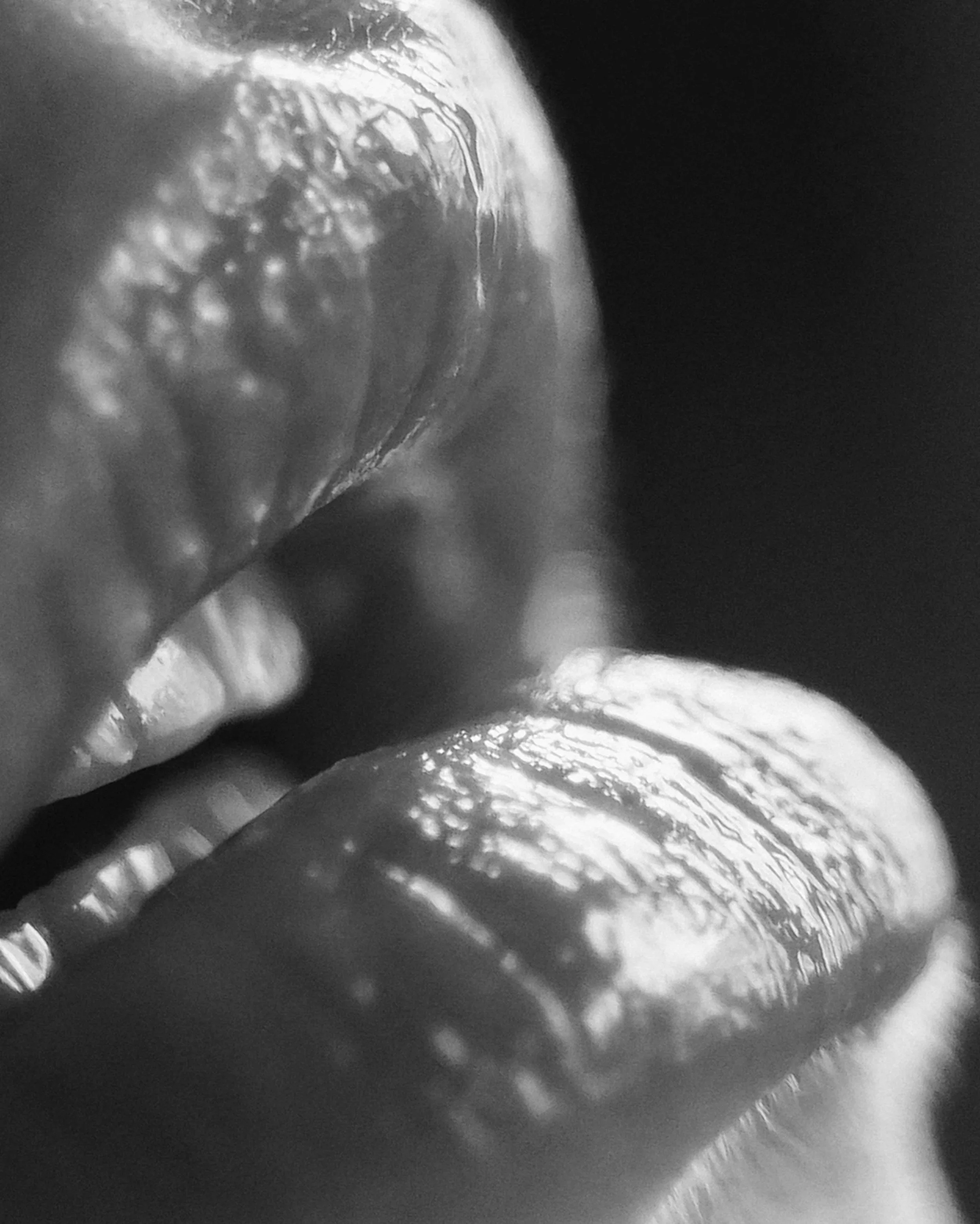 Close-up black and white photo of two fingers touching, showing textured skin and fingernails.