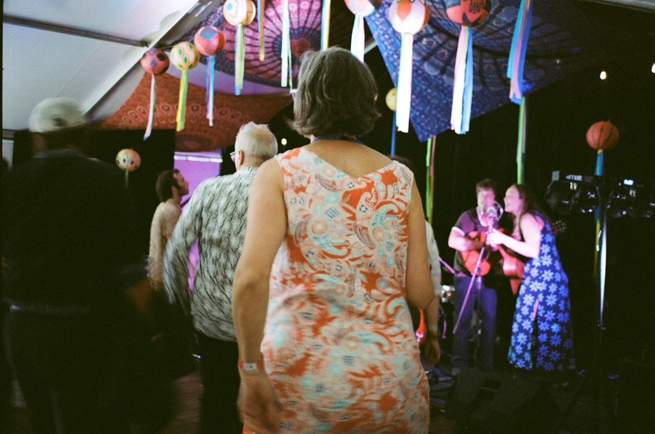 People dancing and enjoying live music performance under colorful paper lantern decorations and umbrellas.
