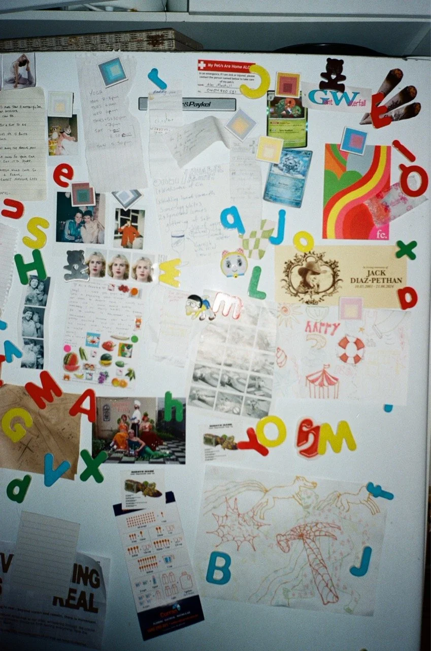 A whiteboard decorated with colorful alphabet foam letters, photos, drawings, notes, and various paper clippings, suggesting a creative or personal space.