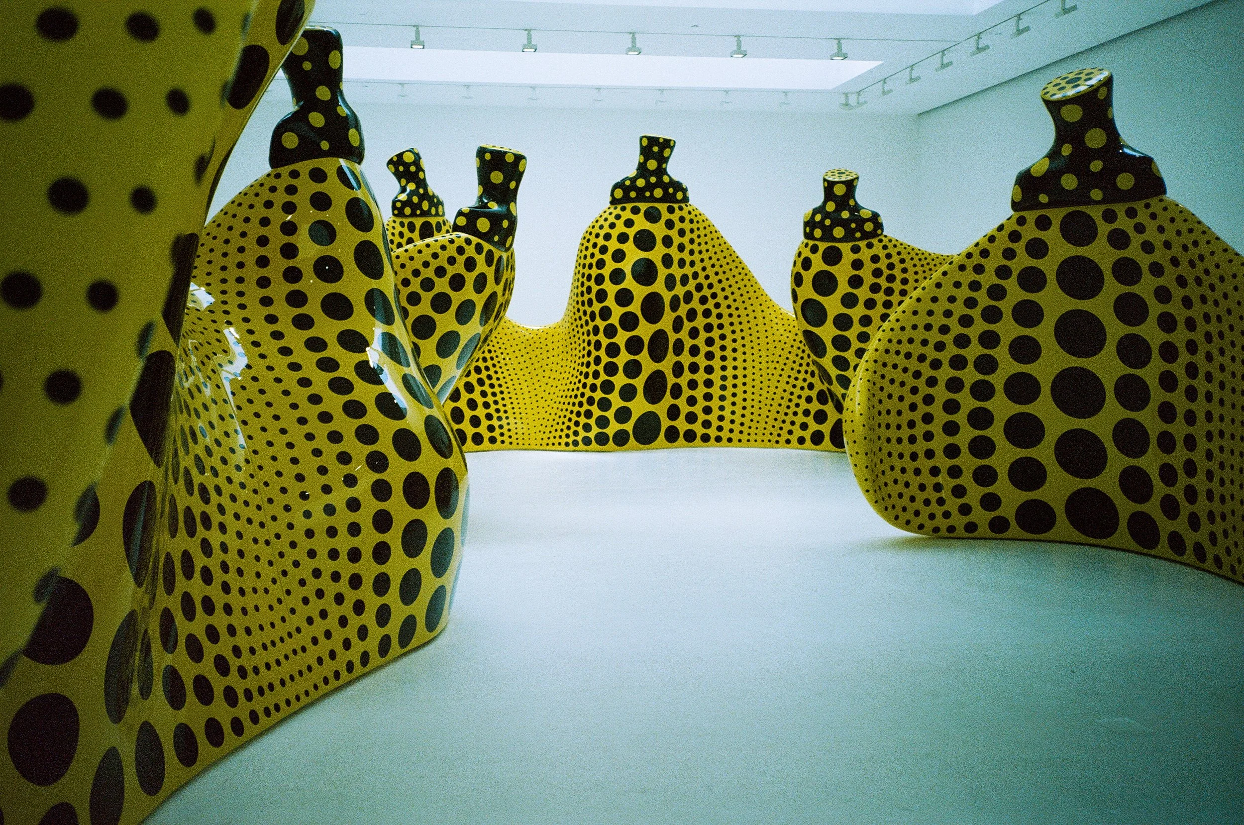 Room filled with large, rounded sculptures painted yellow with black dots in various sizes.