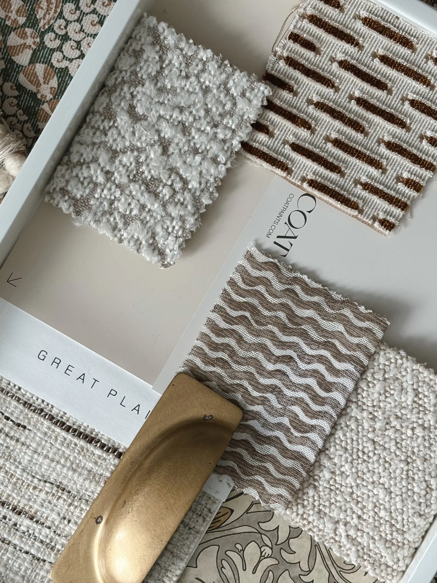 A color palette with various fabric samples including textured and patterned materials, a wooden paint stirrer, and a tray labeled 'Great Plains'.