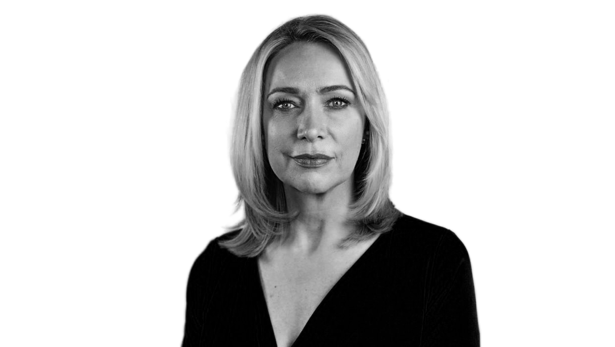 Black and white portrait of a blonde woman with shoulder-length hair, wearing a dark top, looking directly at the camera with a neutral expression.