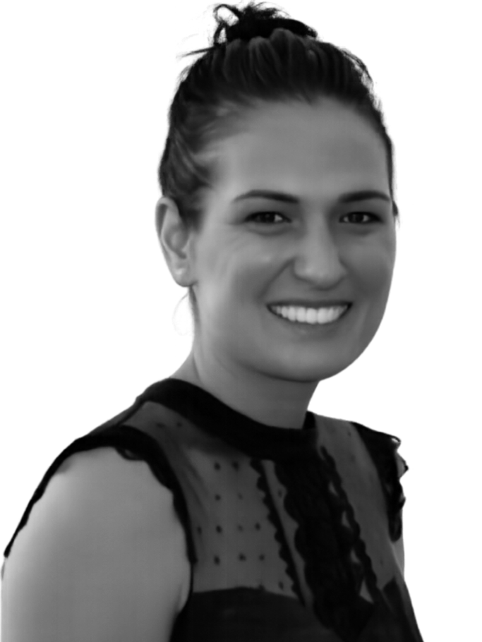 A smiling woman with dark hair tied up, wearing a sheer black top with lace details.