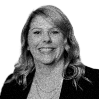 Black and white photo of a smiling woman with shoulder-length wavy hair wearing a blazer.