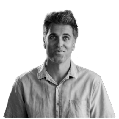 Black and white photograph of a young man with styled hair, wearing a button-up shirt, smiling slightly, against a plain background.
