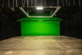Empty photo or film studio with green screen backdrop and black curtained walls