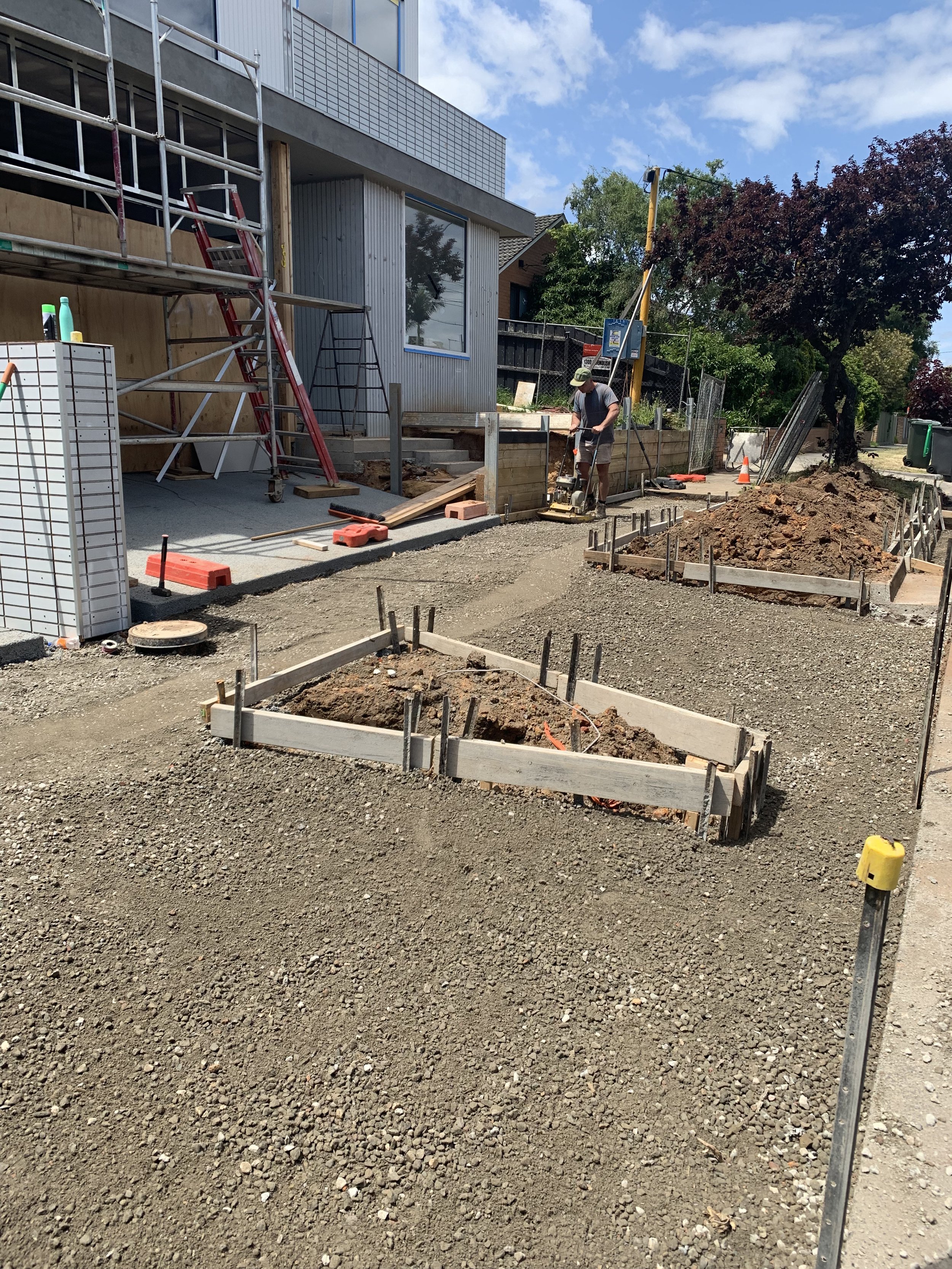 Construction site with wooden frames, tools, and workers preparing ground for building or landscaping.