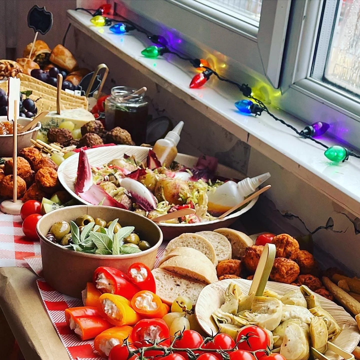 An Intimate Wedding Graze Table with various foods including tomatoes, stuffed peppers, olives, artichokes, bread, salads