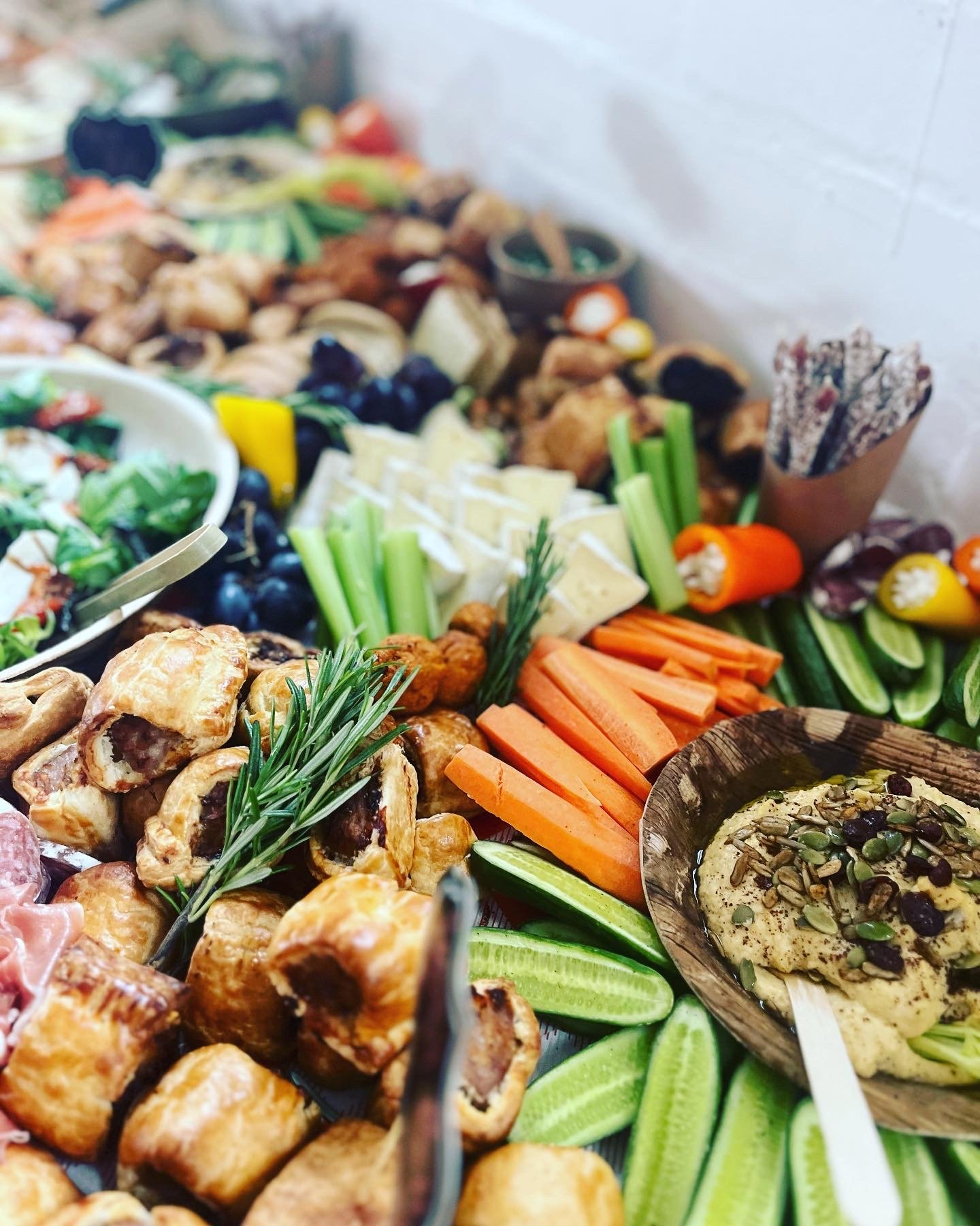 A variety of small appetizers and finger foods arranged on a table, including vegetables, cheeses, and pastries, with some garnished with herbs.