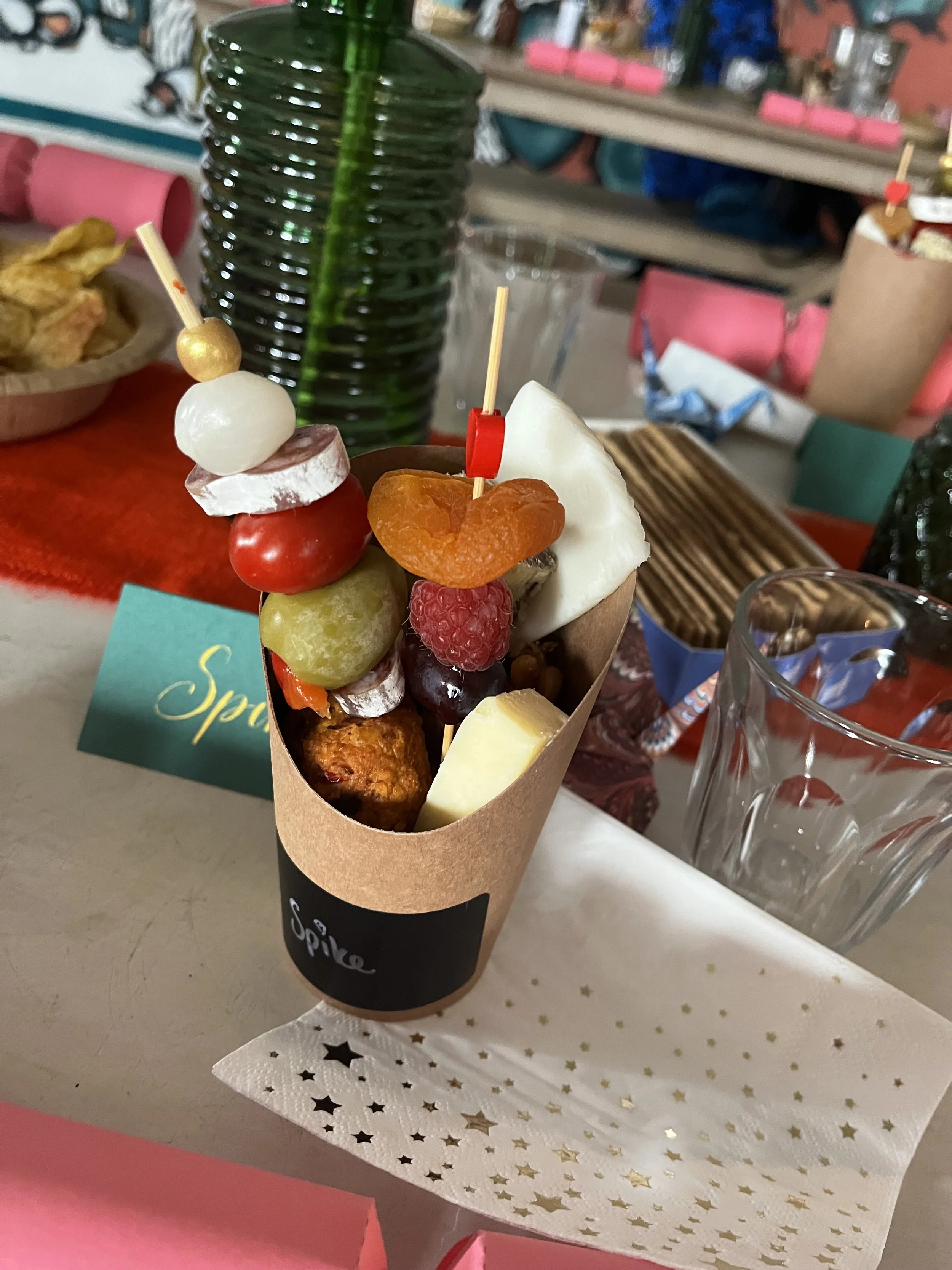 A charcuterie cup with assorted fruits, cheese and cured meats