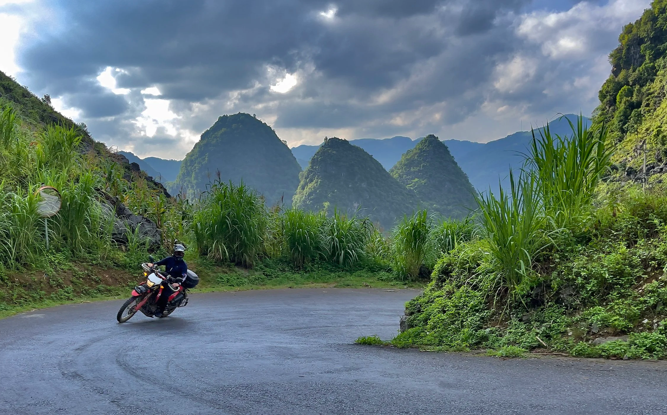Motorbike rider cornering on a mountain road surrounded by dramatic highland scenery.