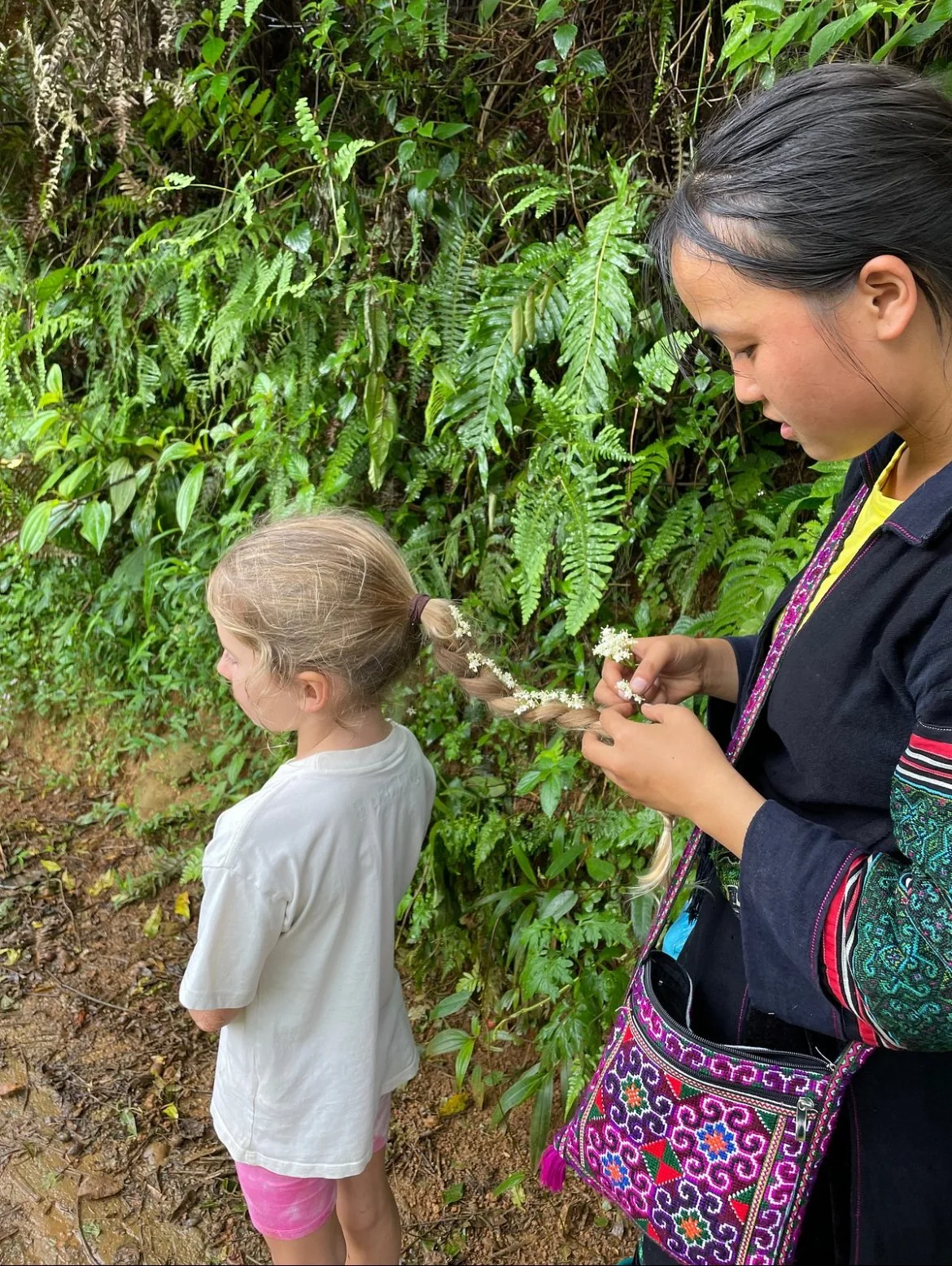 Local woman braiding child’s hair in Sapa village