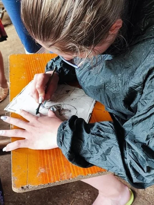 Traveller learning batik on cotton in touristy area.