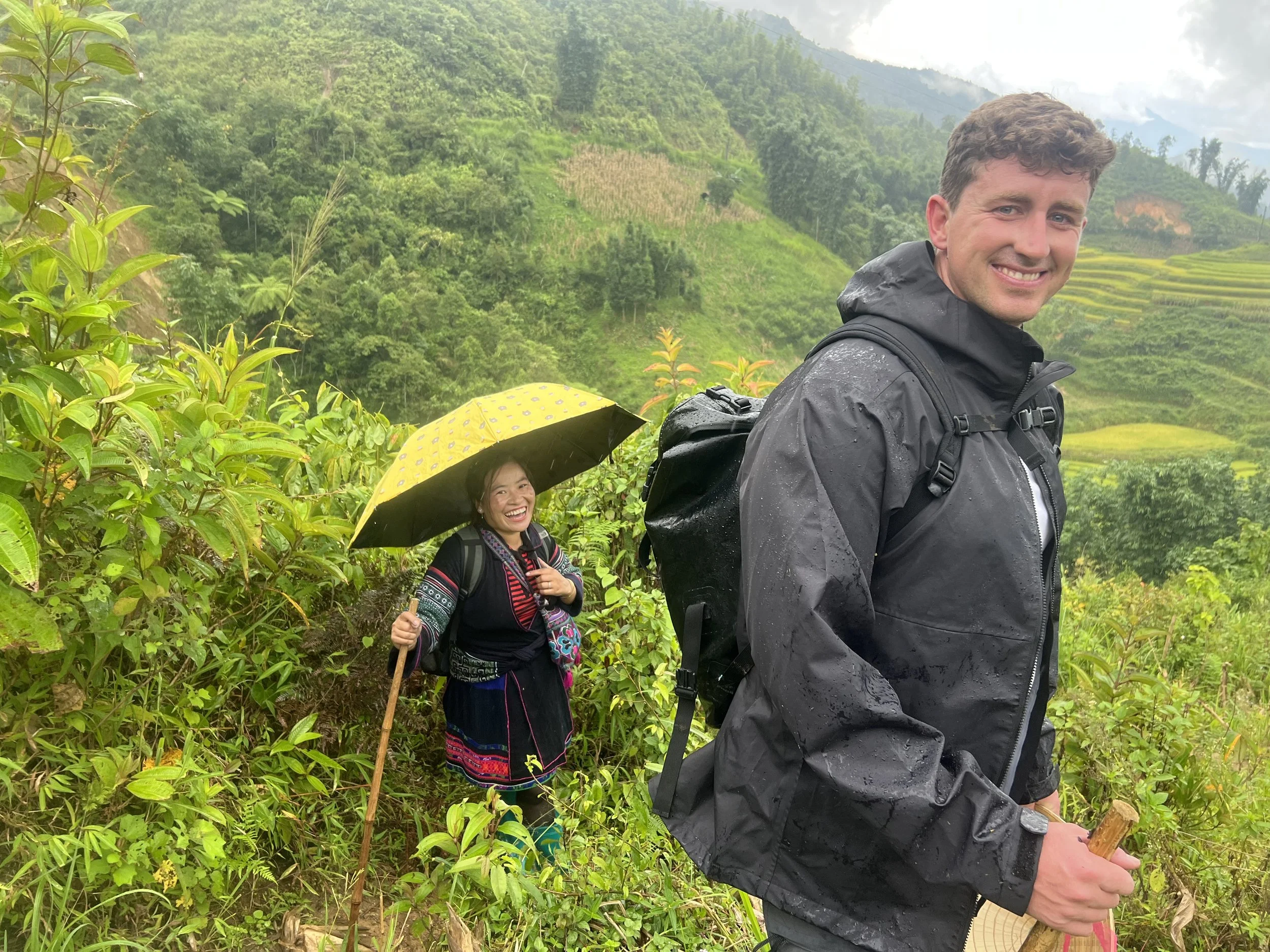 Traveler hiking through lush green rice terraces in Sapa during the growing season.