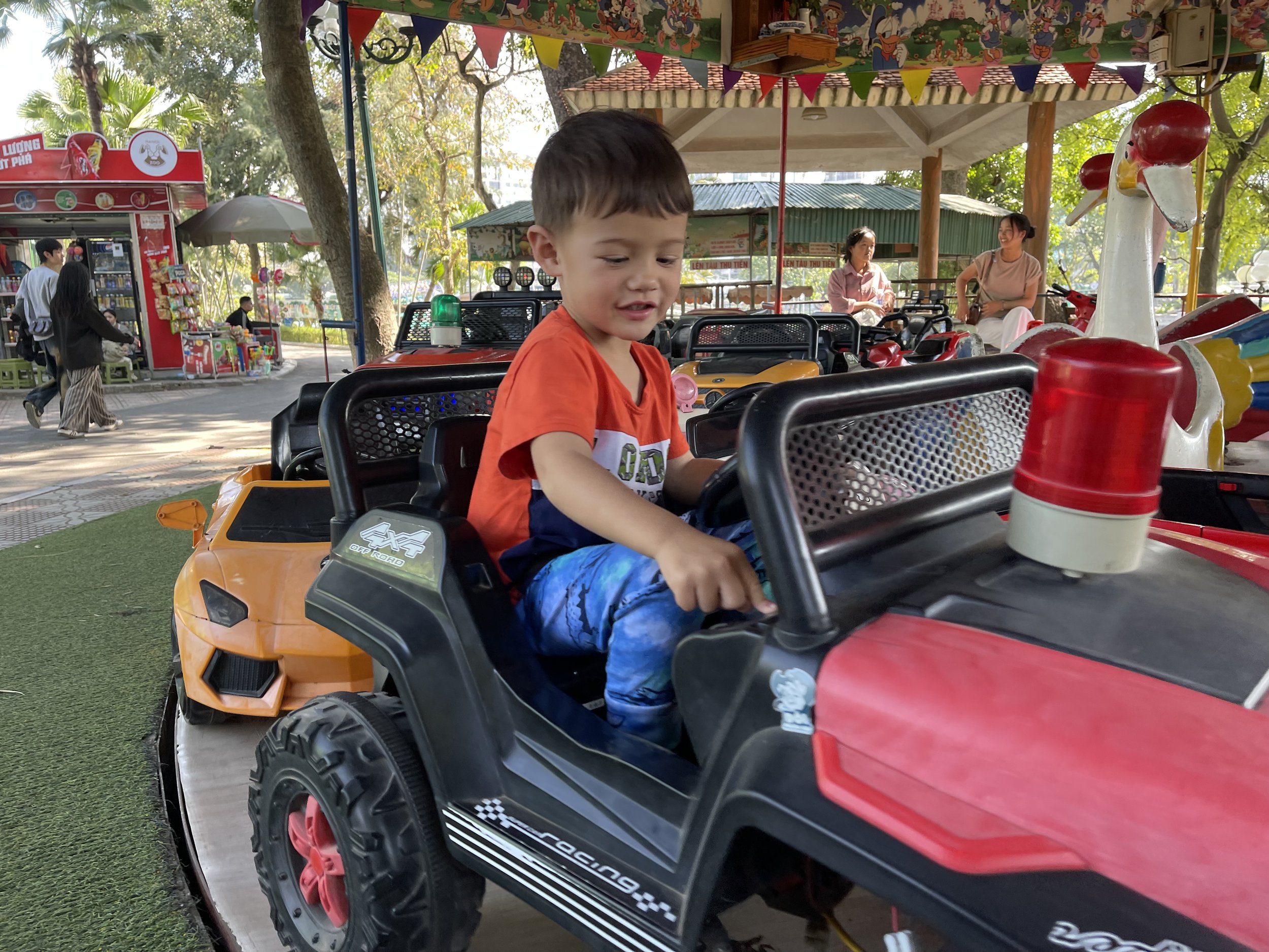 Young child driving toy car in Hanoi park playground