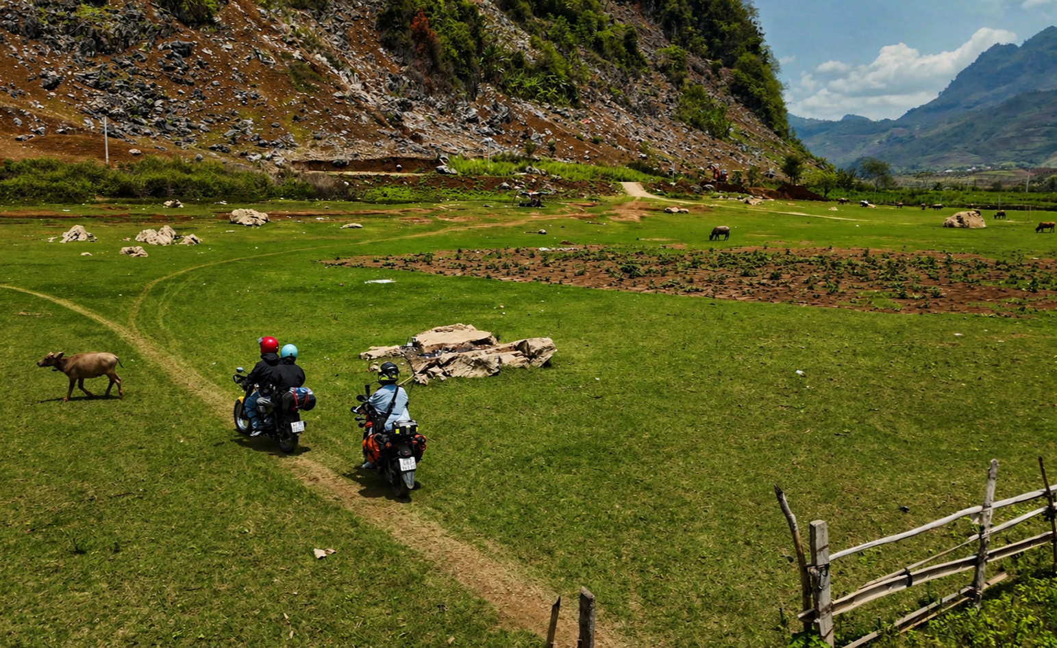 Motorbike riders crossing a cultivated valley in Son La Province, northern Vietnam, with limestone mountains and farmland surrounding the route