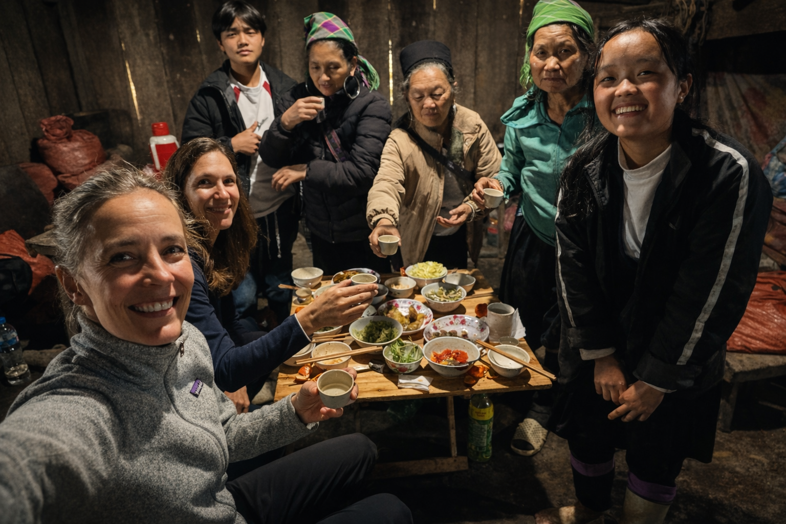 Travelers sharing a traditional meal with local hosts during a homestay experience in Sapa