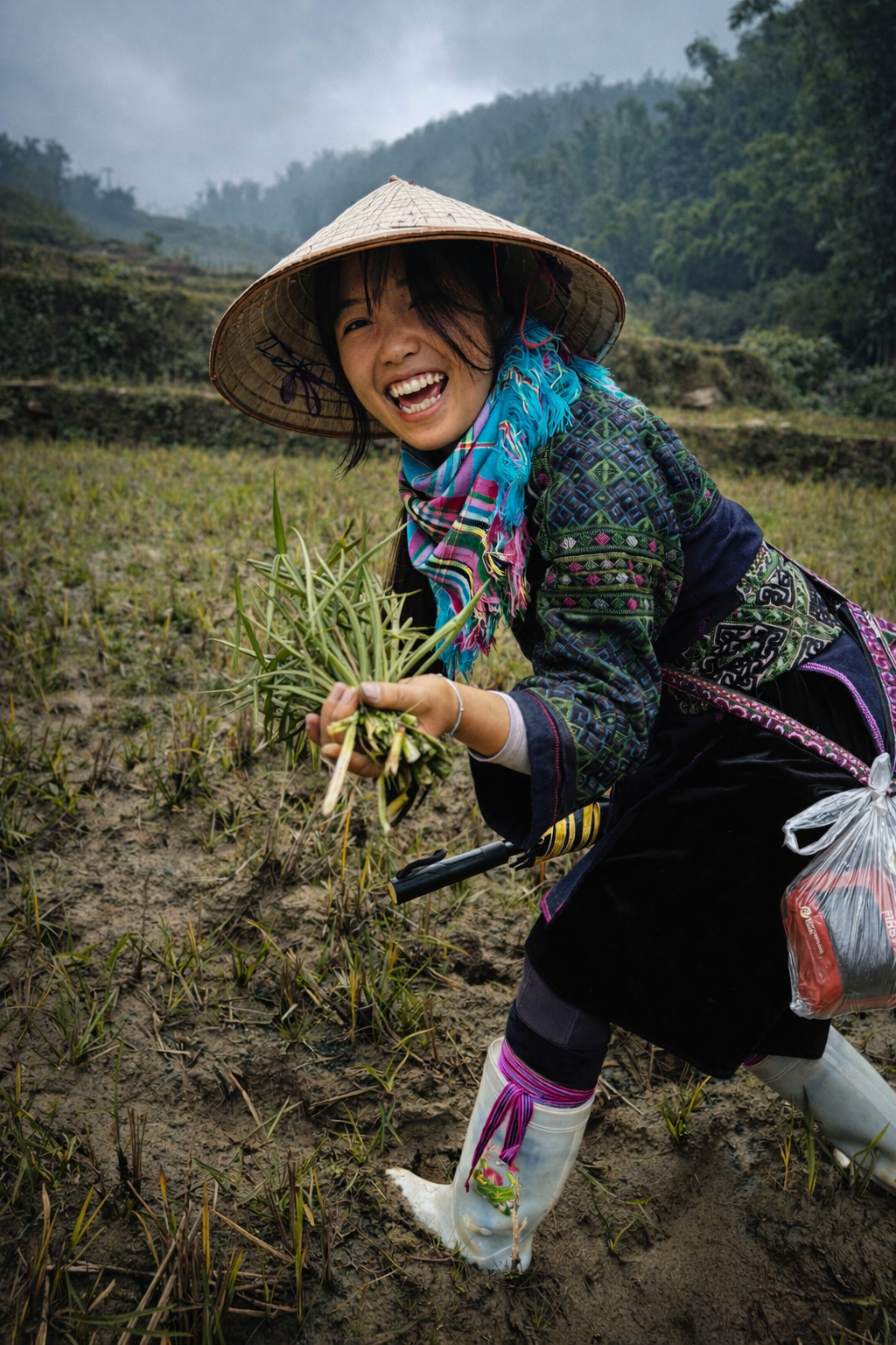 Hmong guide smiling while gathering wild edible plants in muddy rice fields in northern Vietnam.