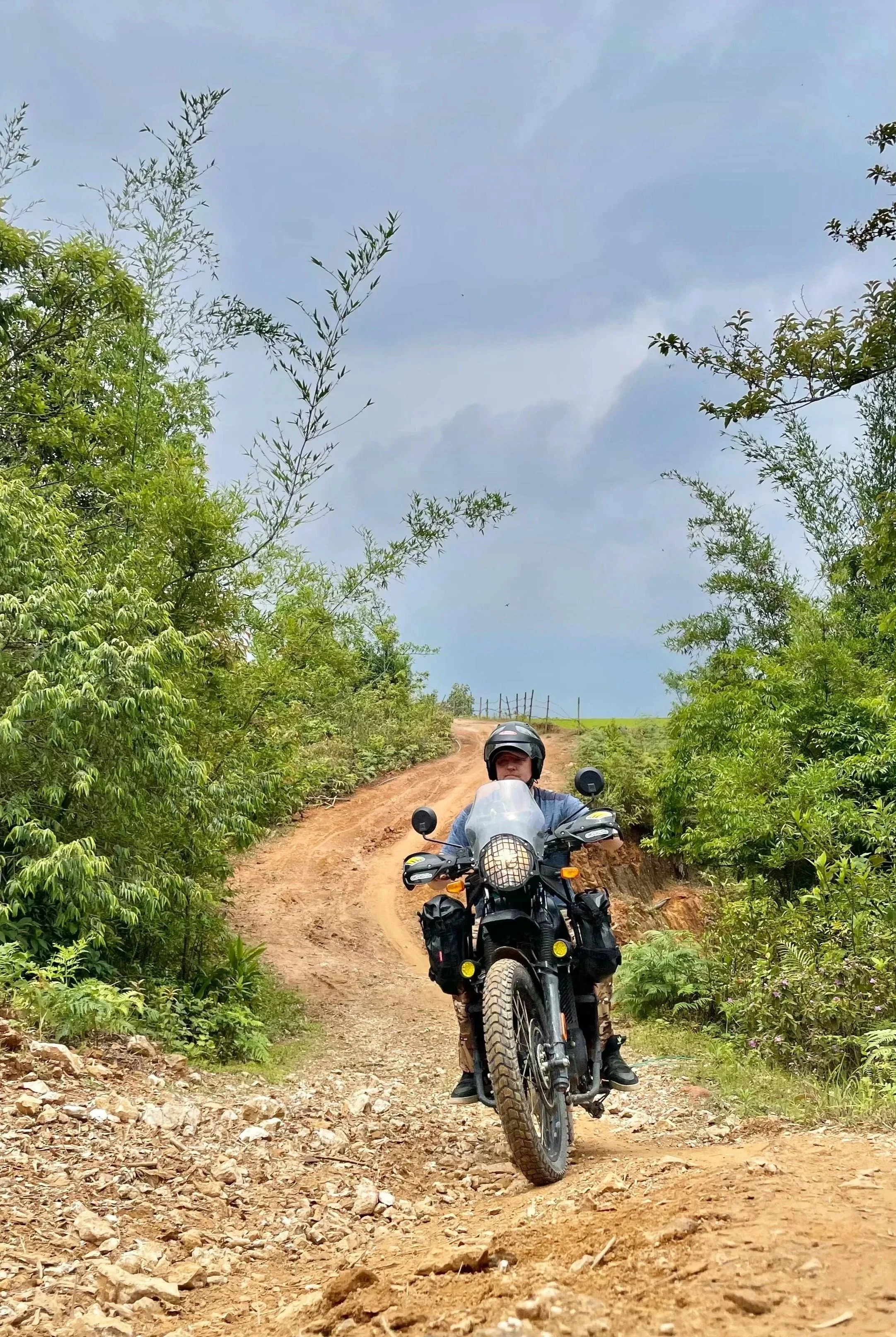 Motorbike rider travelling along a rough dirt track in rural northern Vietnam.