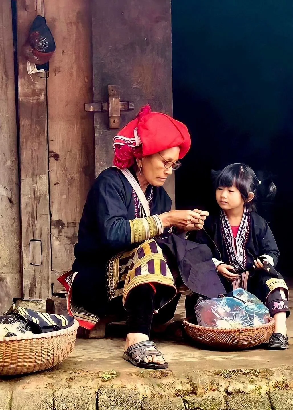 Grandmother teaching her granddaughter traditional embroidery outside their home in Northern Vietnam.