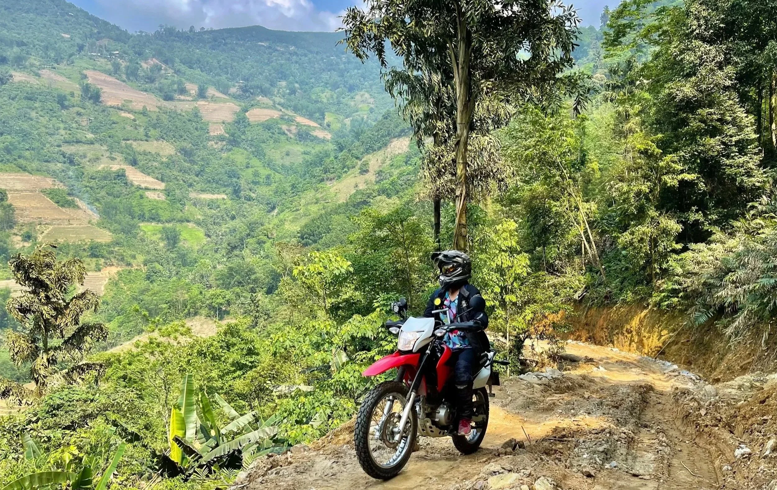 Motorbike rider overlooking a green mountain valley in northern Vietnam.