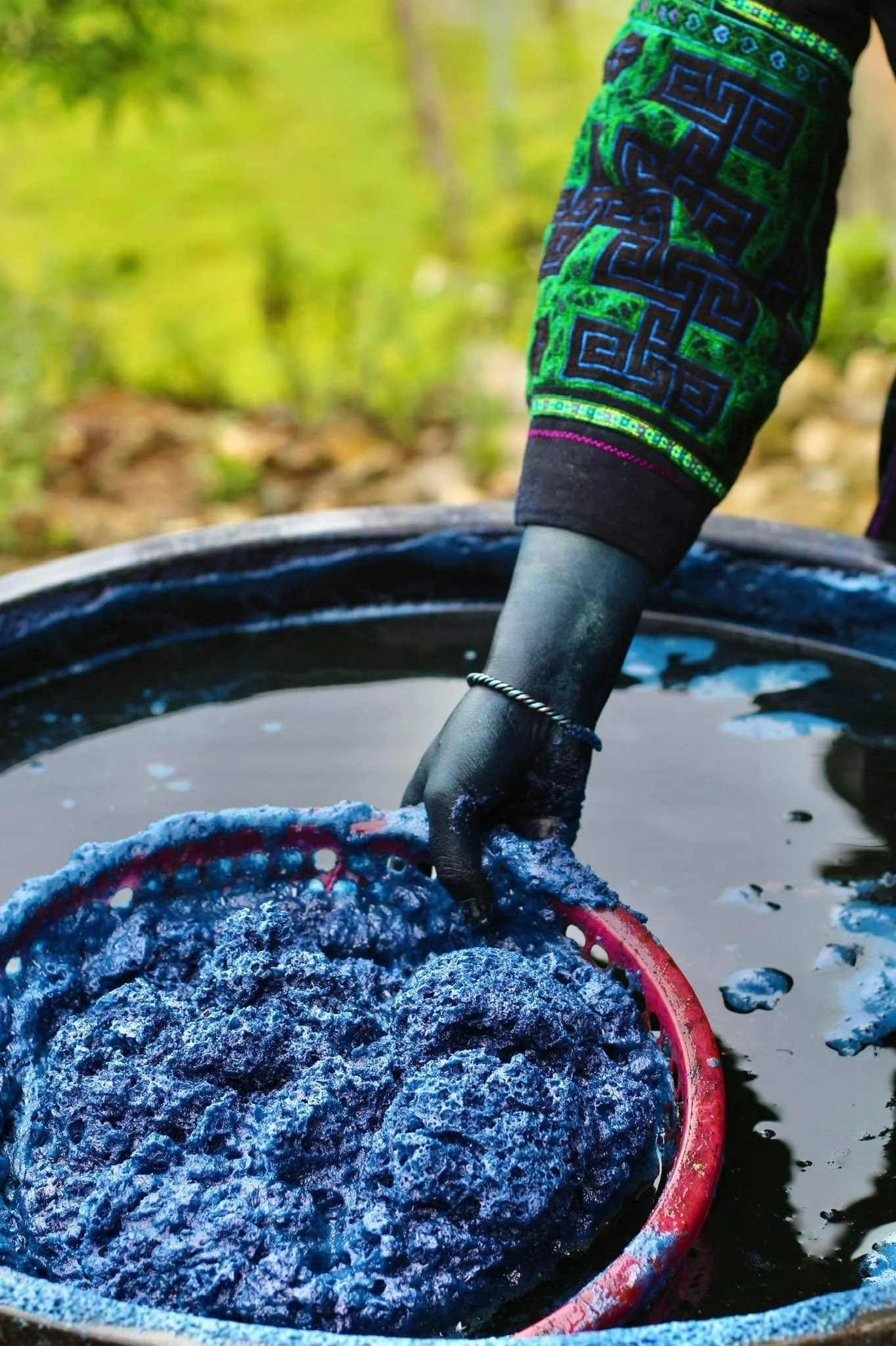 A Hmong woman preparing indigo vat for dyeing fabric.