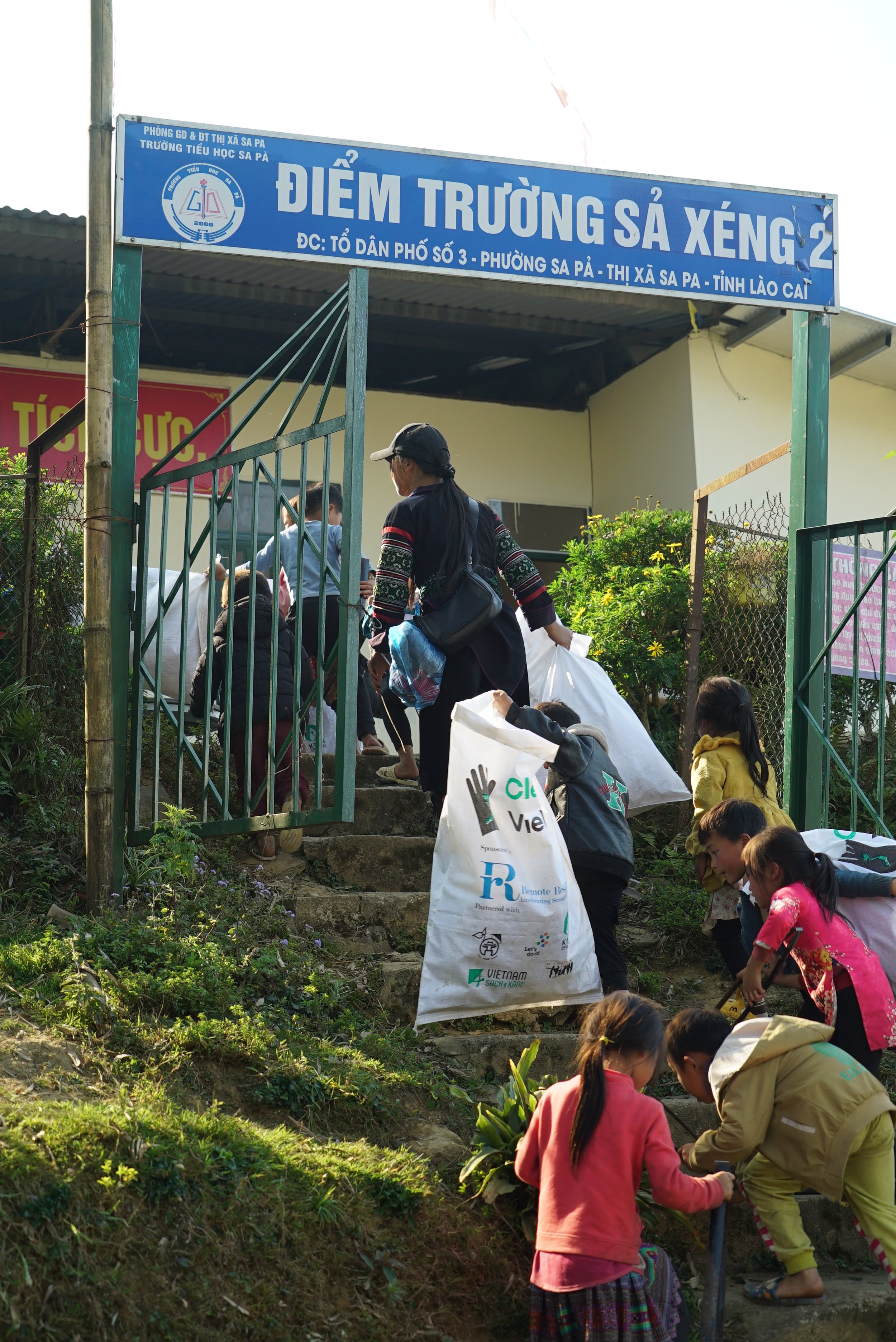 Hmong children and local women carrying collected rubbish bags to the Sà Xéng 2 village school in Sapa.