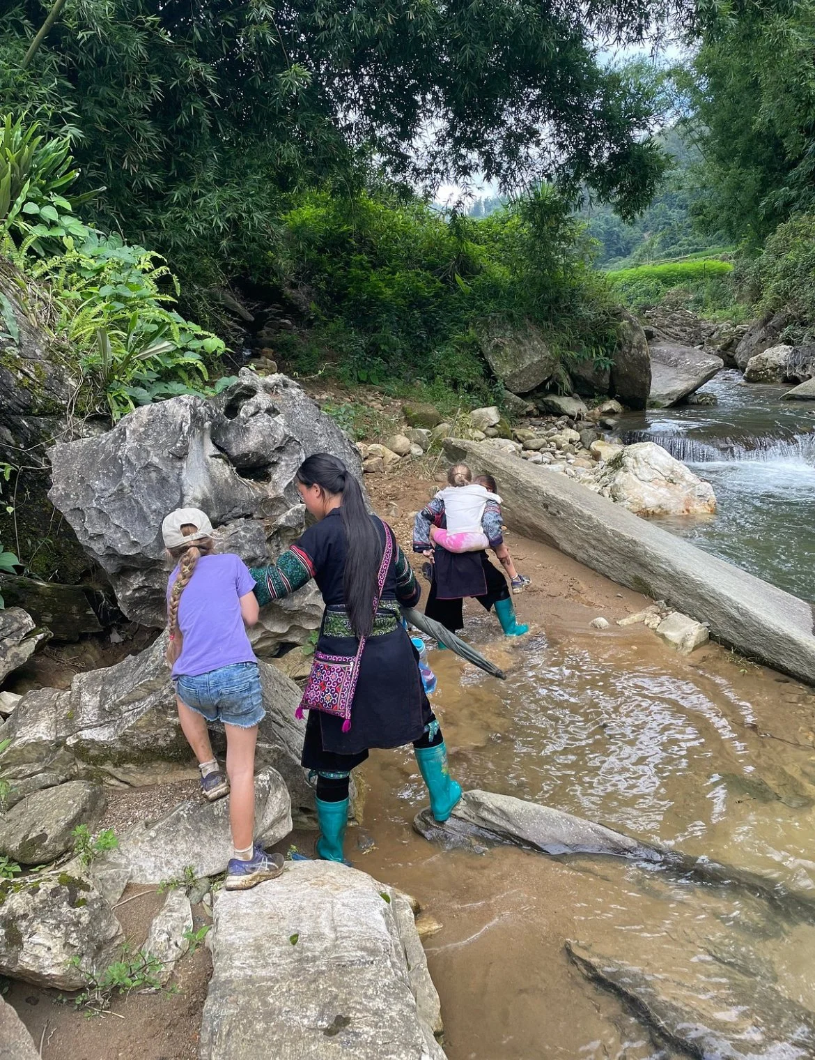 Children exploring rocks and stream in forest area