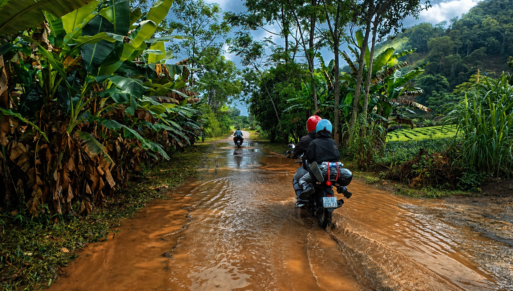 Riders navigating a muddy road through dense tropical vegetation after rain.