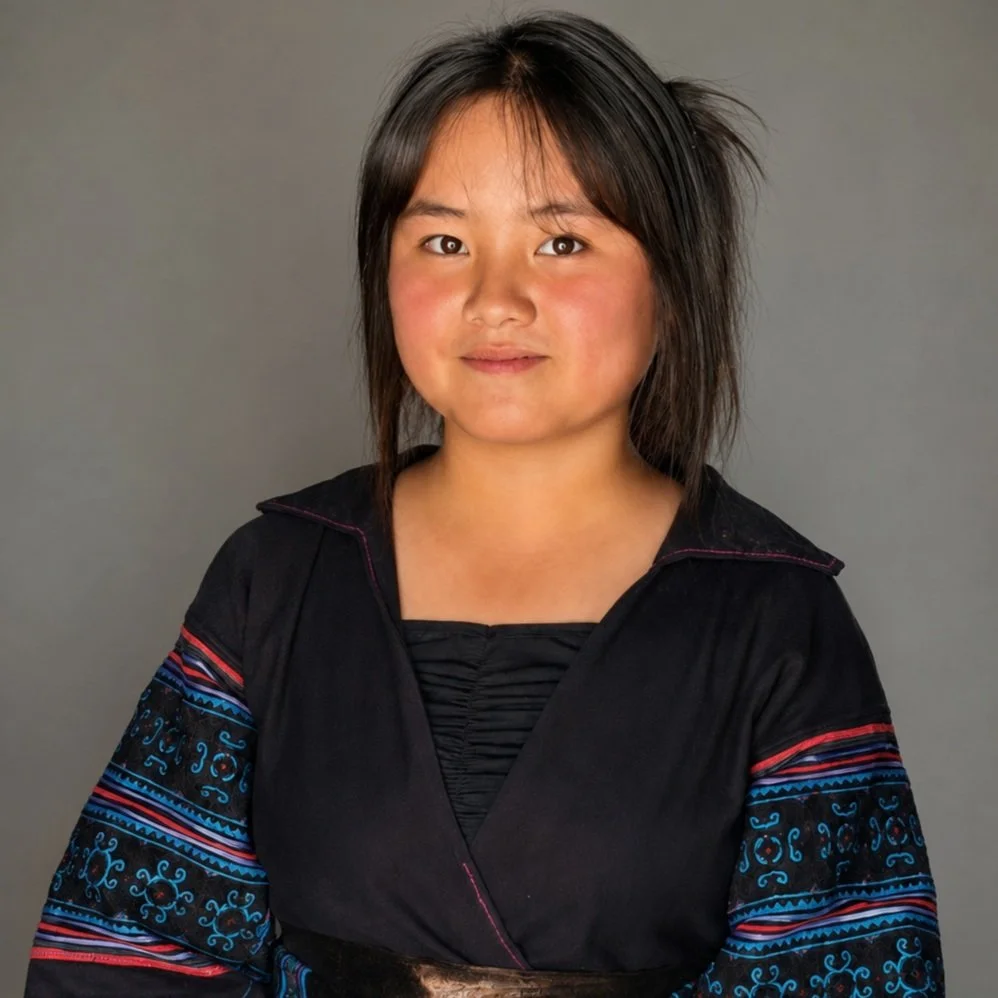 Lý Thị Pằng smiles inside her family home in Pa Cheo while wearing traditional Black Hmong clothing.