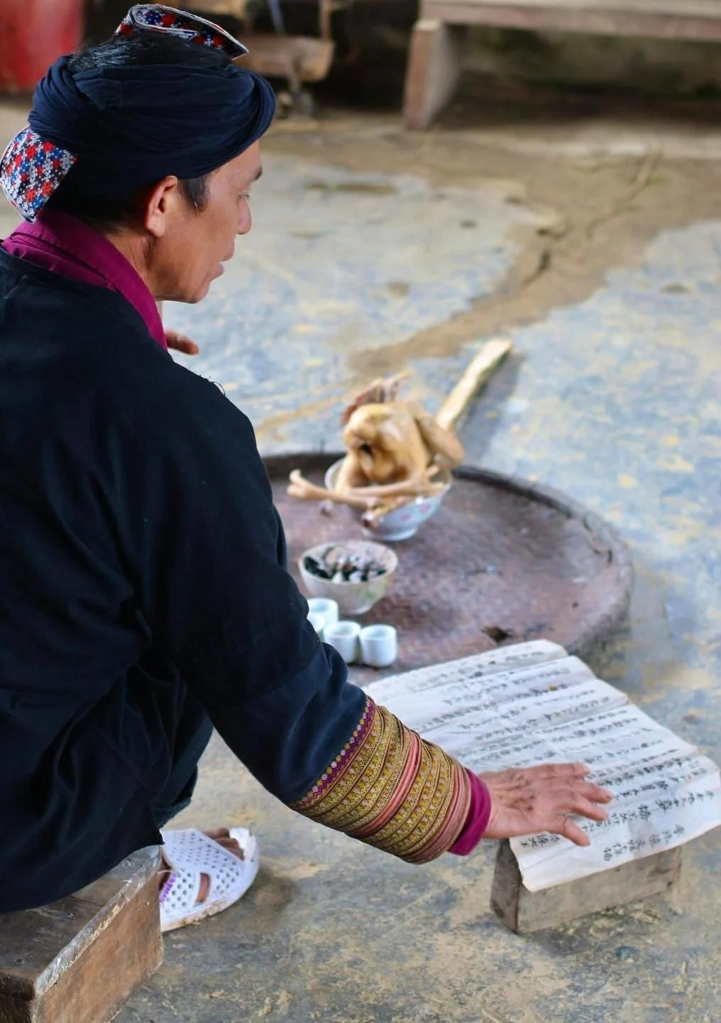 Red Dao ritual master reading from a handwritten ceremonial manuscript during a traditional religious ceremony in Sa Pa, northern Vietnam.