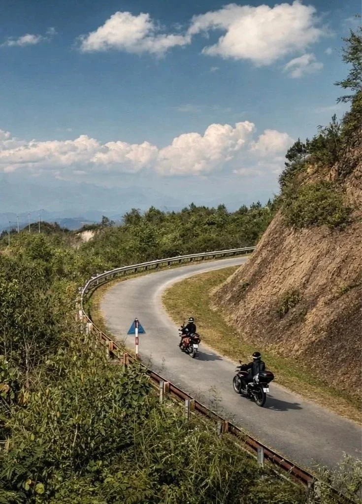 Two motorbikes descending a curving mountain pass in Vietnam’s northern highlands.