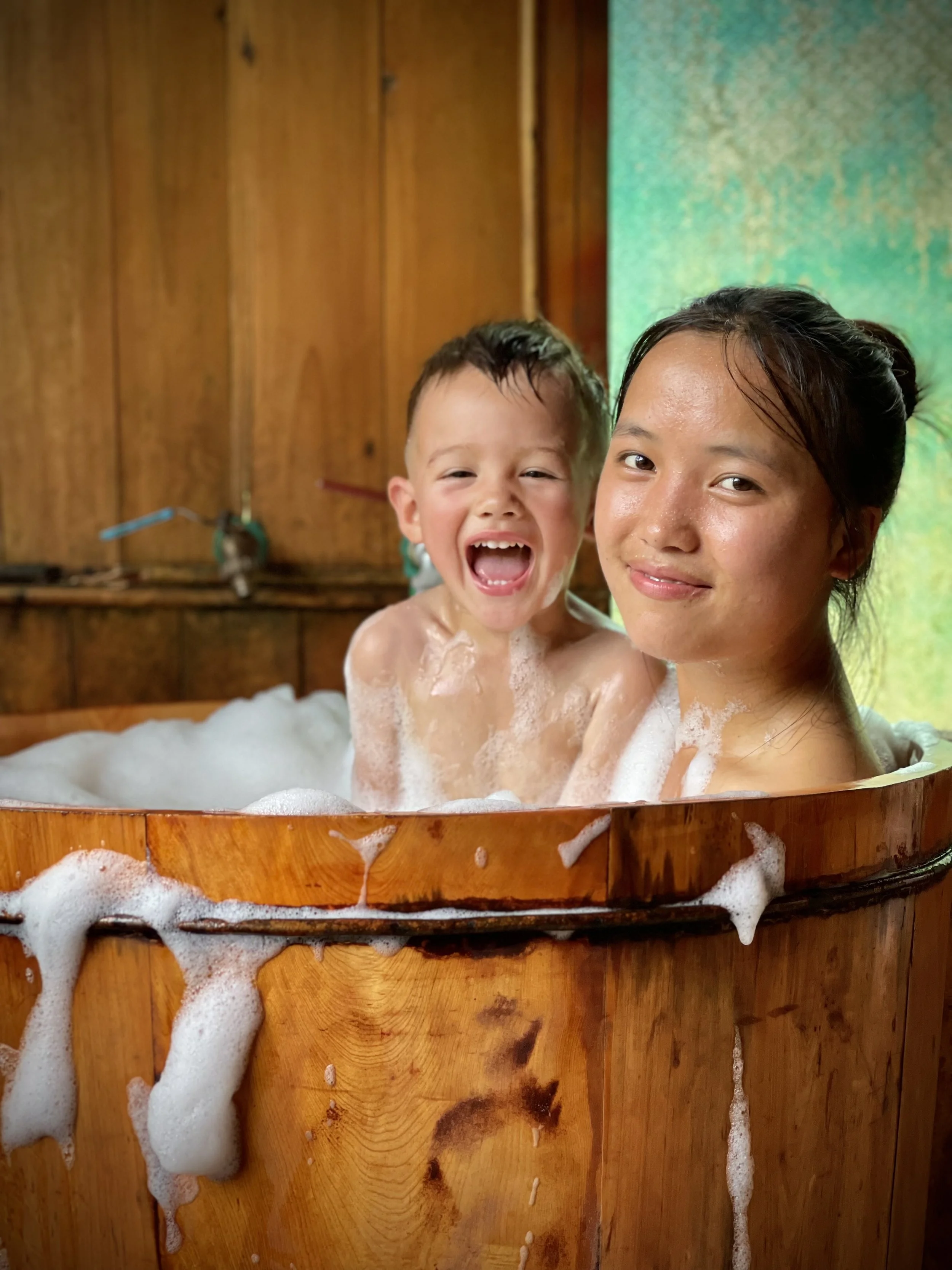 Sister and child relaxing in traditional Red Dao herbal bath